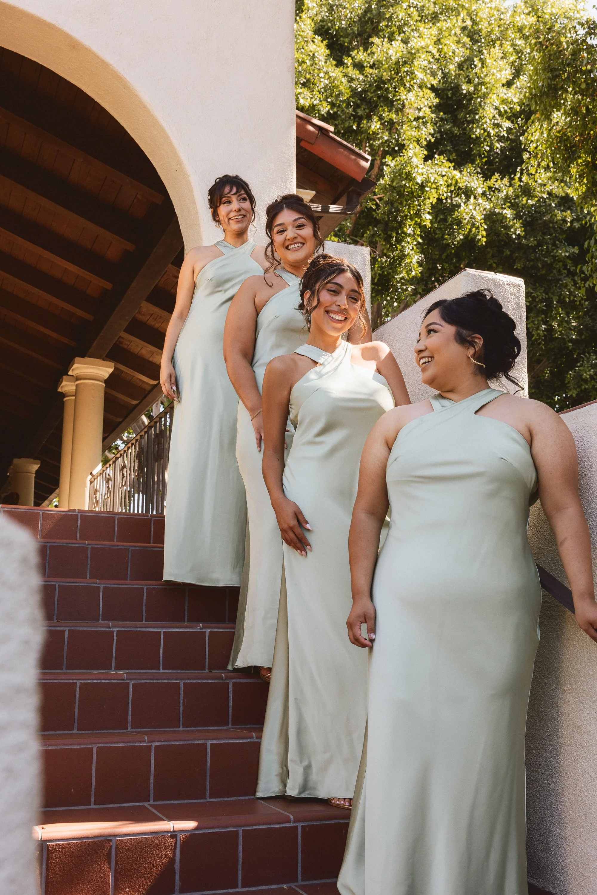 Bridesmaids in sage dresses walking down stairs at Los Angeles River Center