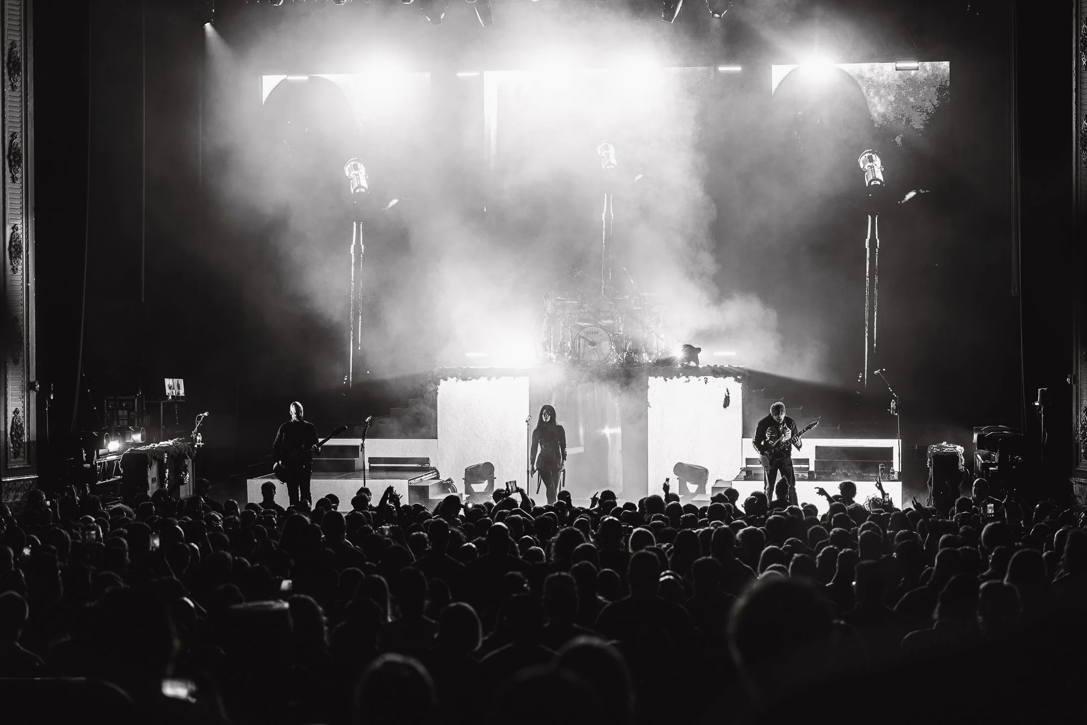Black and white photo of a live concert with a band on stage and a large audience in front.