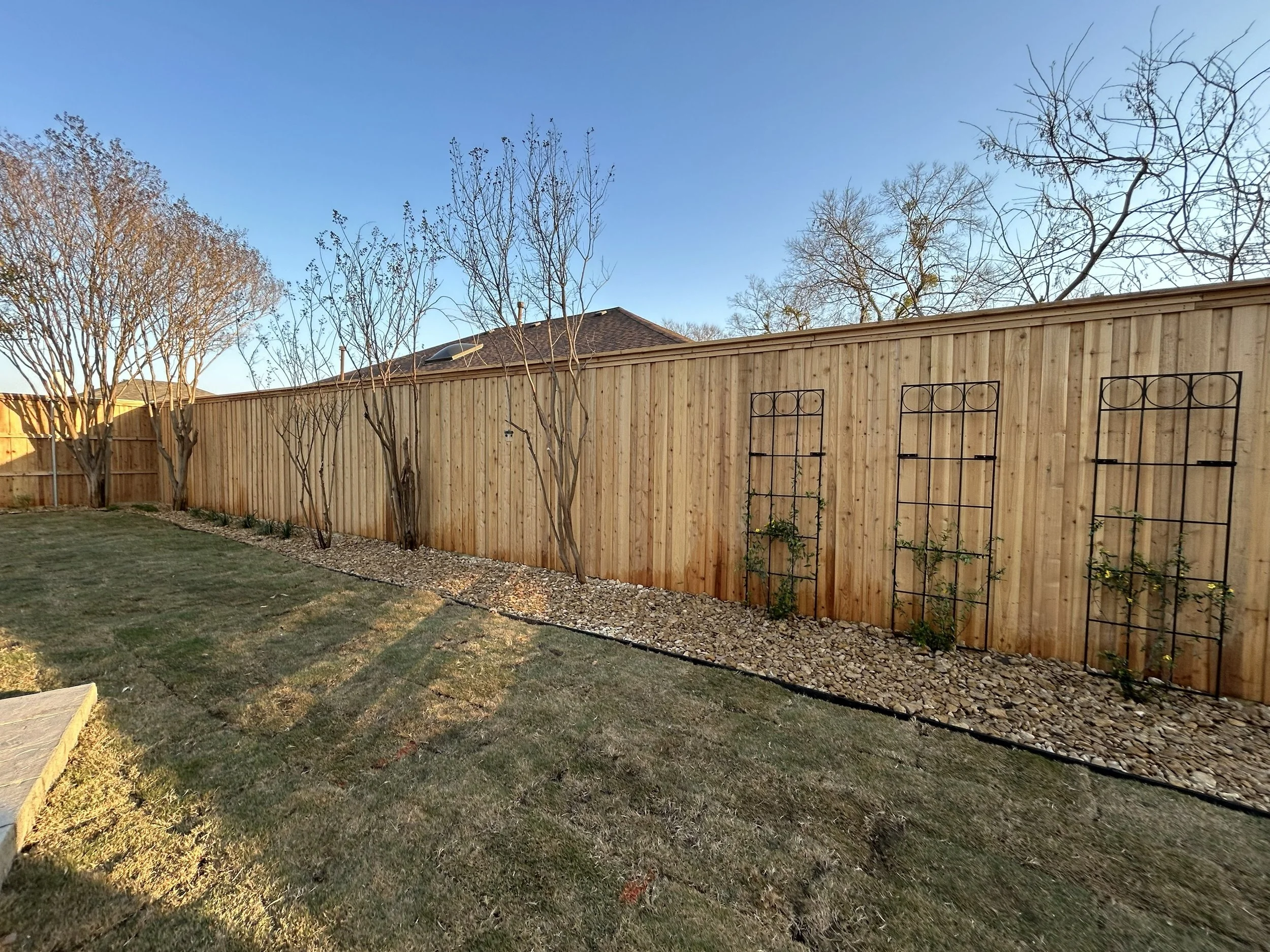 After photos showing results of back yard transformation. New fence, landscape beds, gravel, plants, vine, and trellis