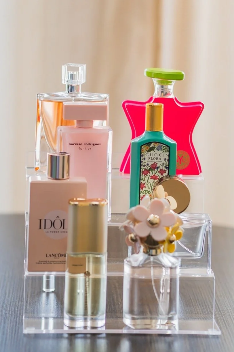 Collection of various perfume bottles on a clear display stand.