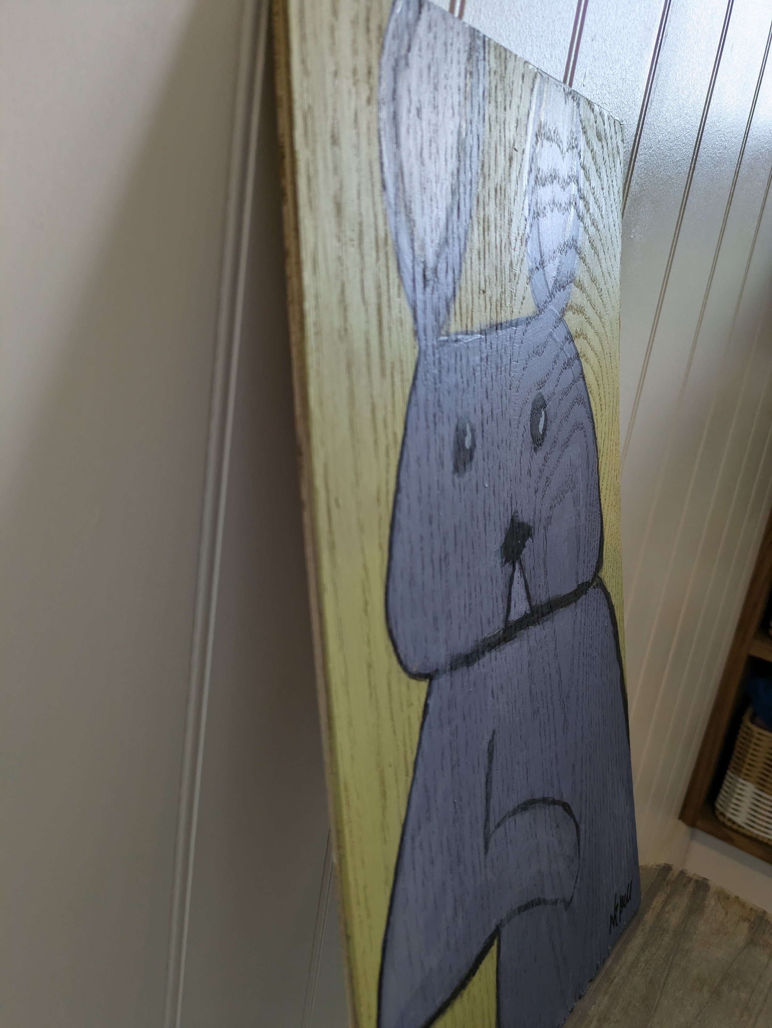 A wood panel with a colourful bunny illustration painted on it.
