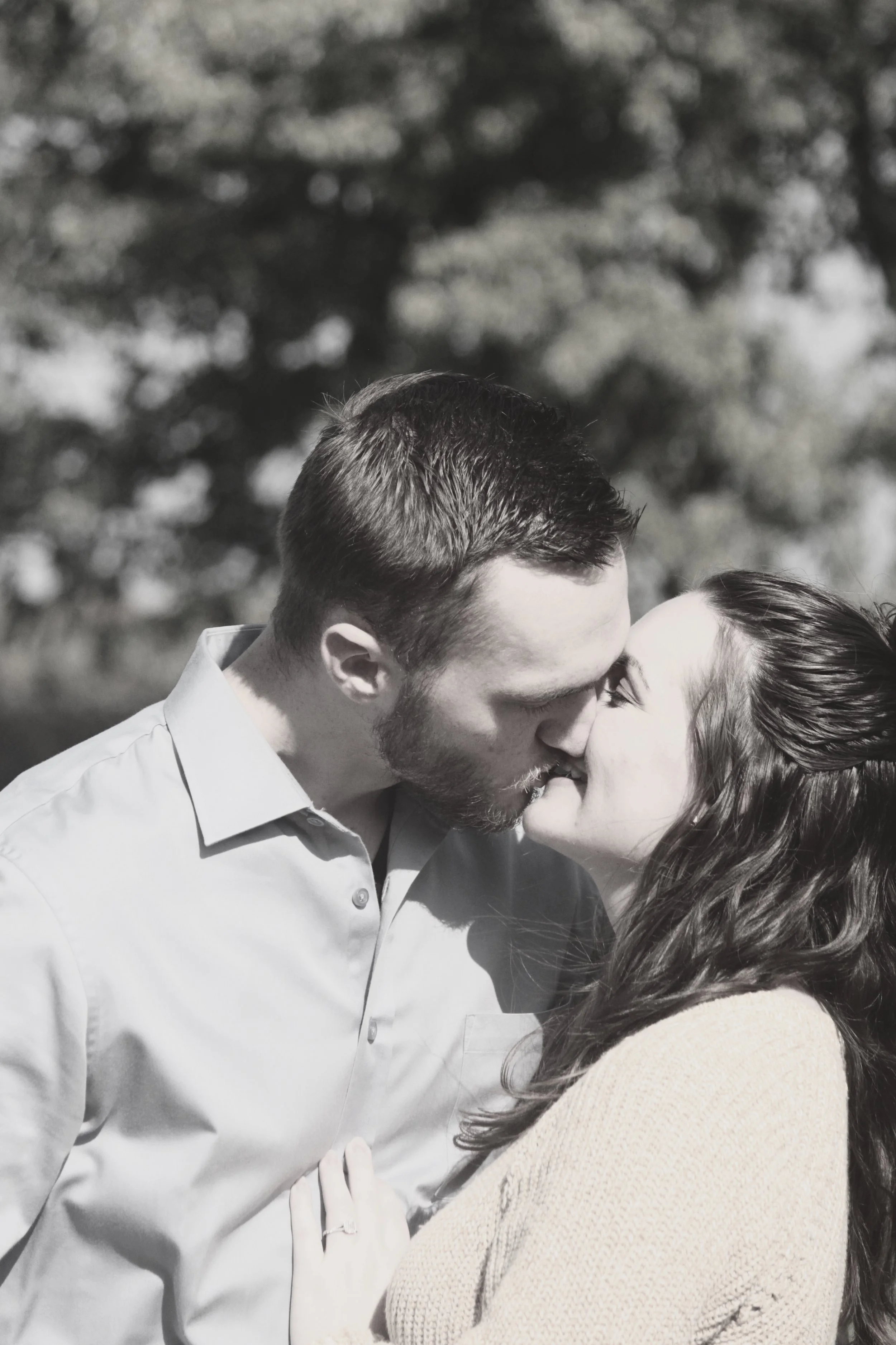 A man and woman sharing a kiss outdoors, black and white photograph.
