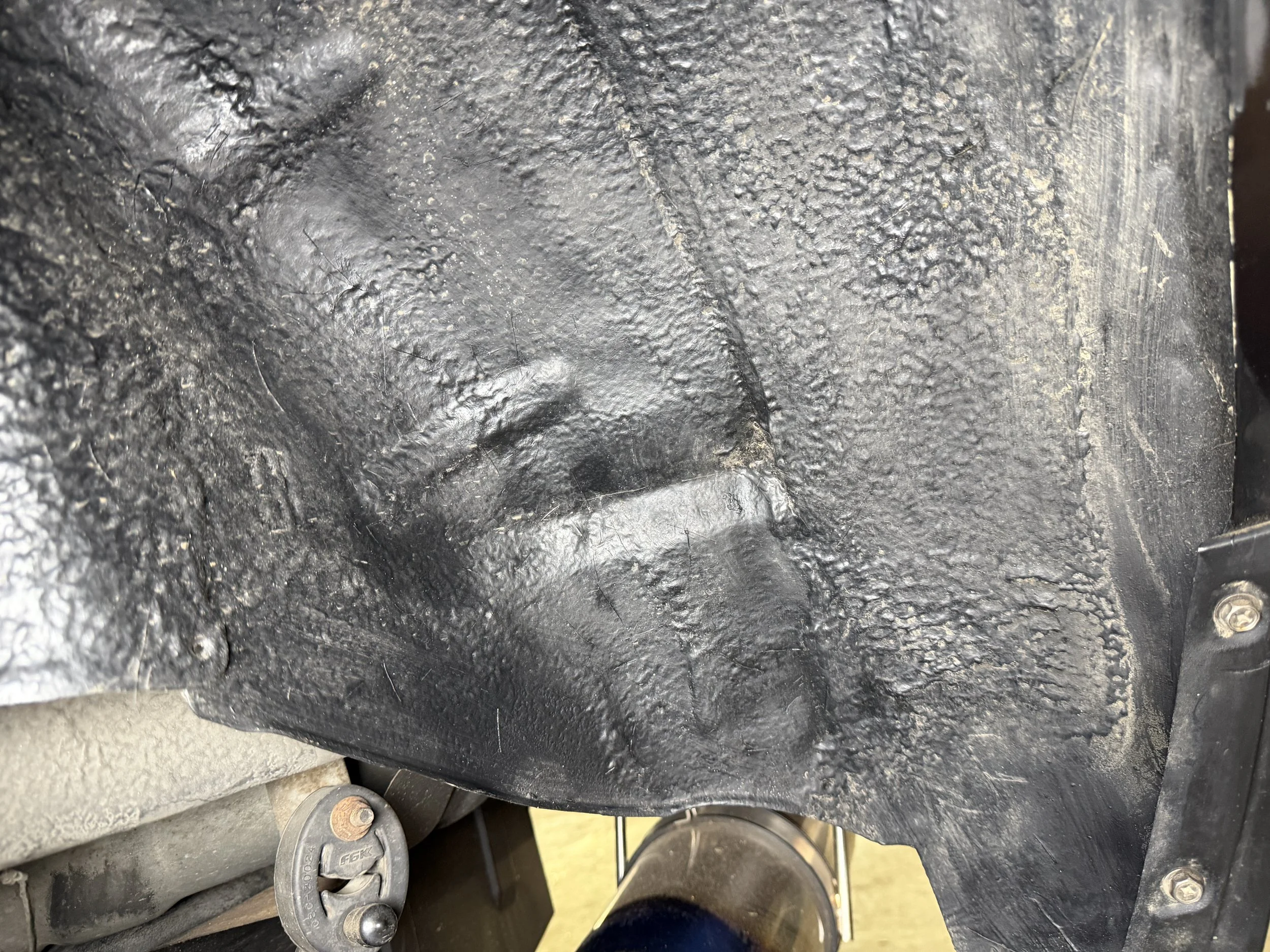 A textured black plastic or rubber surface with a raised face outline and a keyhole, possibly a cover or panel on a machine or vehicle.