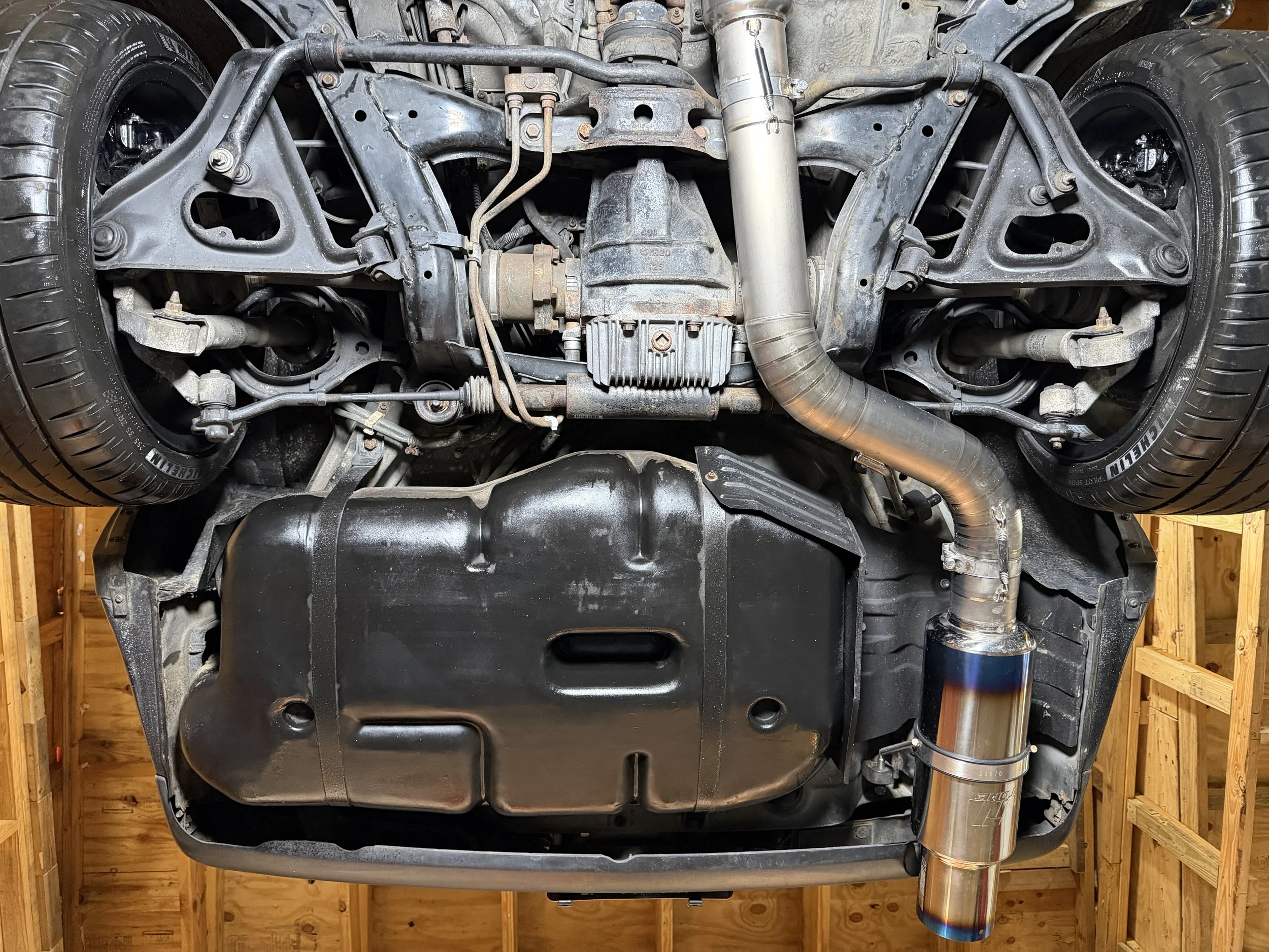 Underside of a car showing engine, suspension, and exhaust system components.