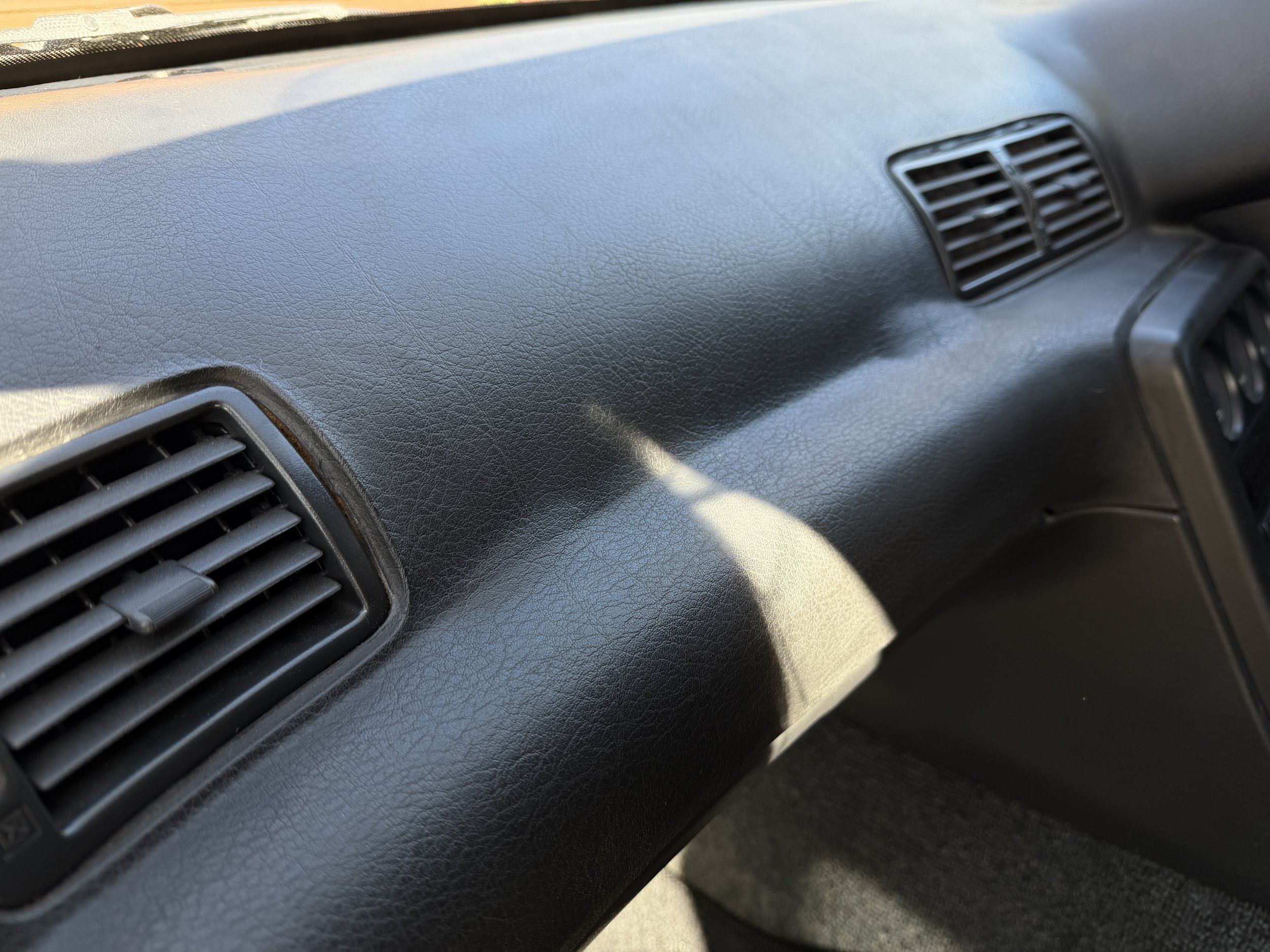 Close-up of a black car dashboard with air vents.