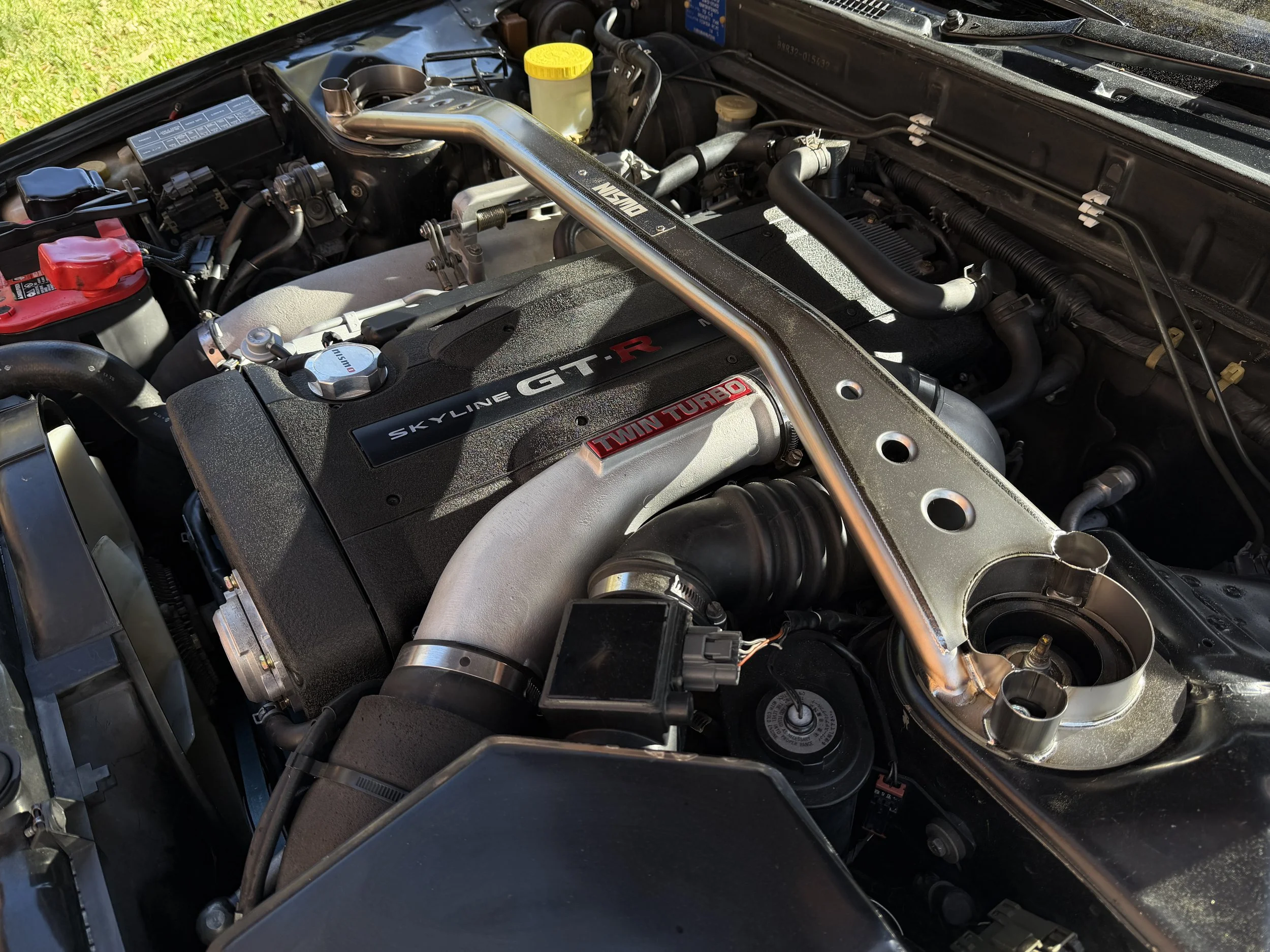 Engine bay of a Nissan Skyline GT-R with a twin turbo setup and a custom strut brace.