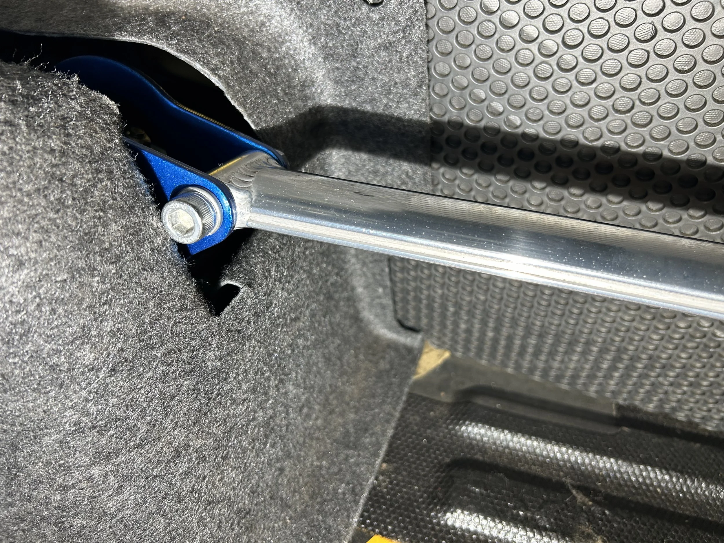 Close-up of a metal toggle switch attached to a black textured surface with a bolt and a blue metallic component.