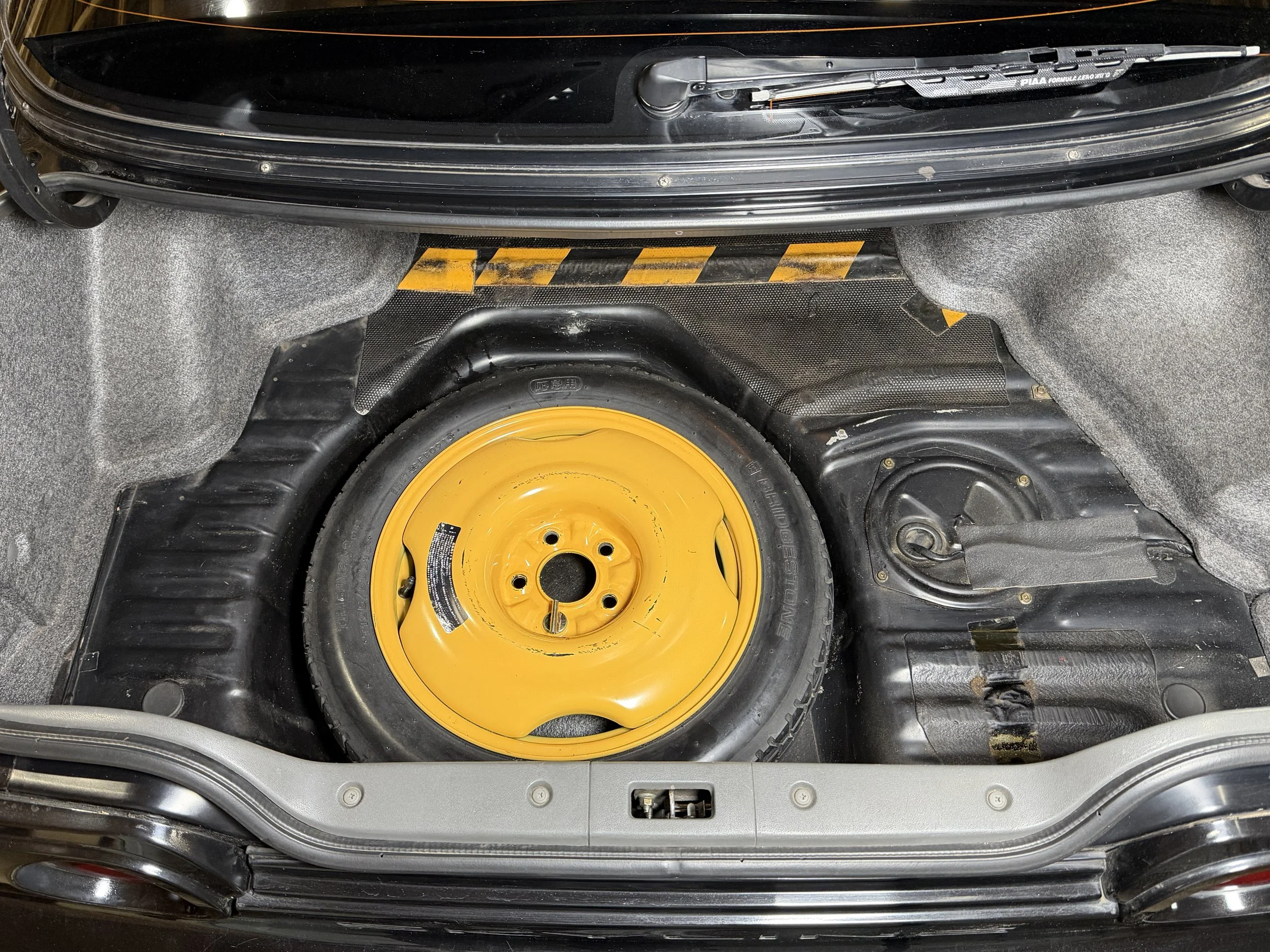 Spare tire stored in the trunk of a vehicle.