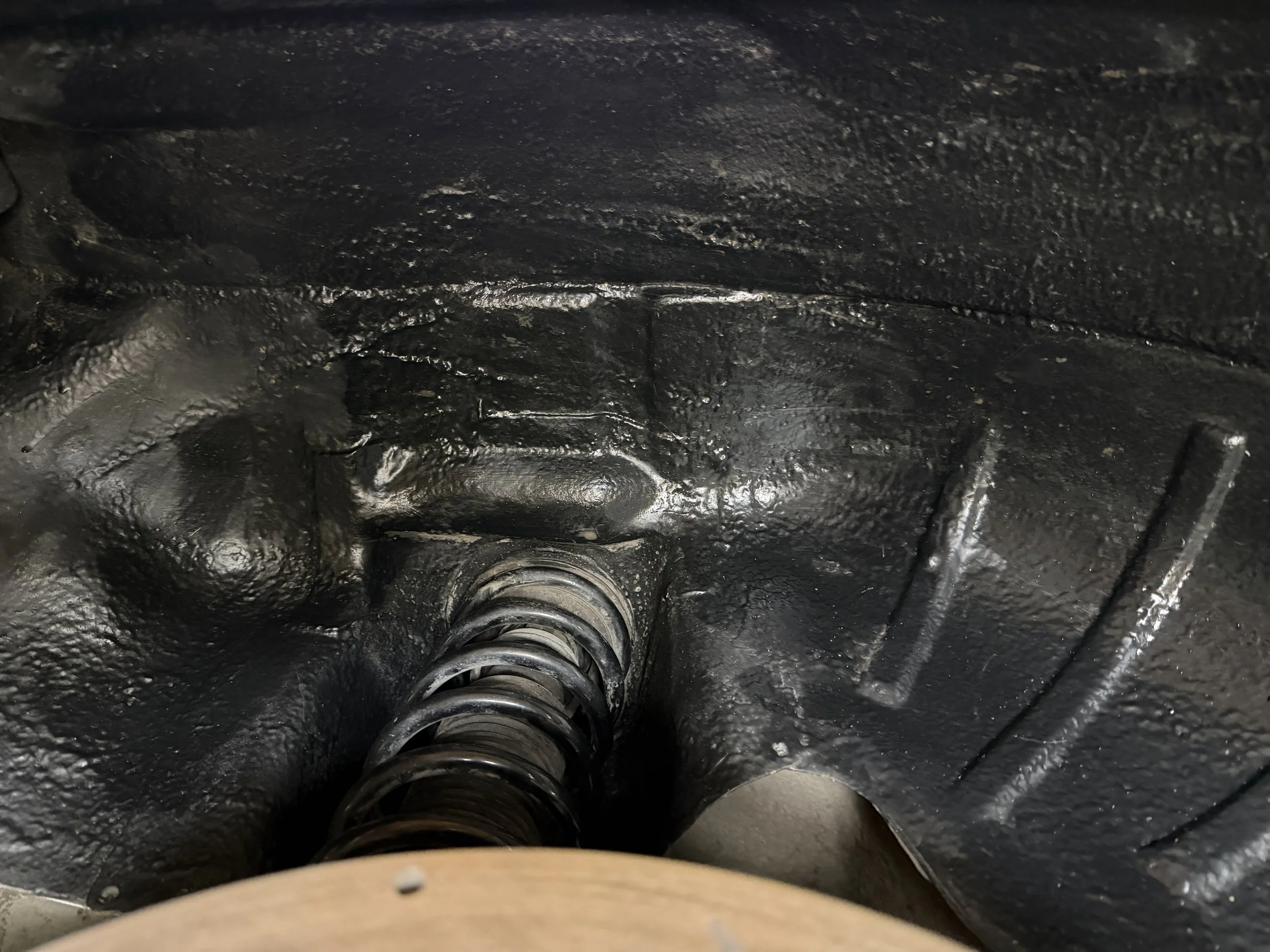 Close-up of a mechanical part with a spring inside a metallic housing, painted black.