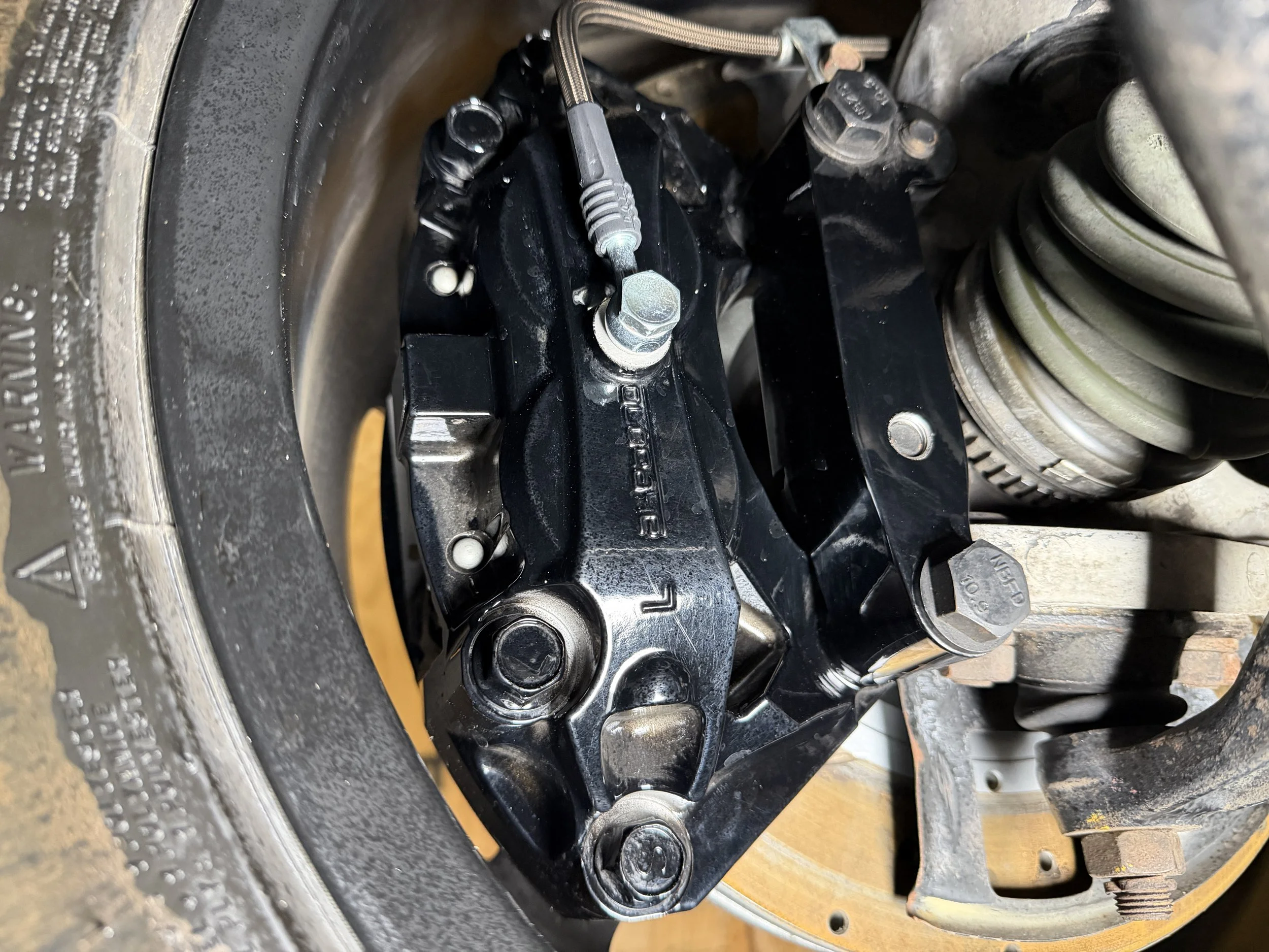 Close-up of a vehicle's suspension system with a black control arm and coil spring