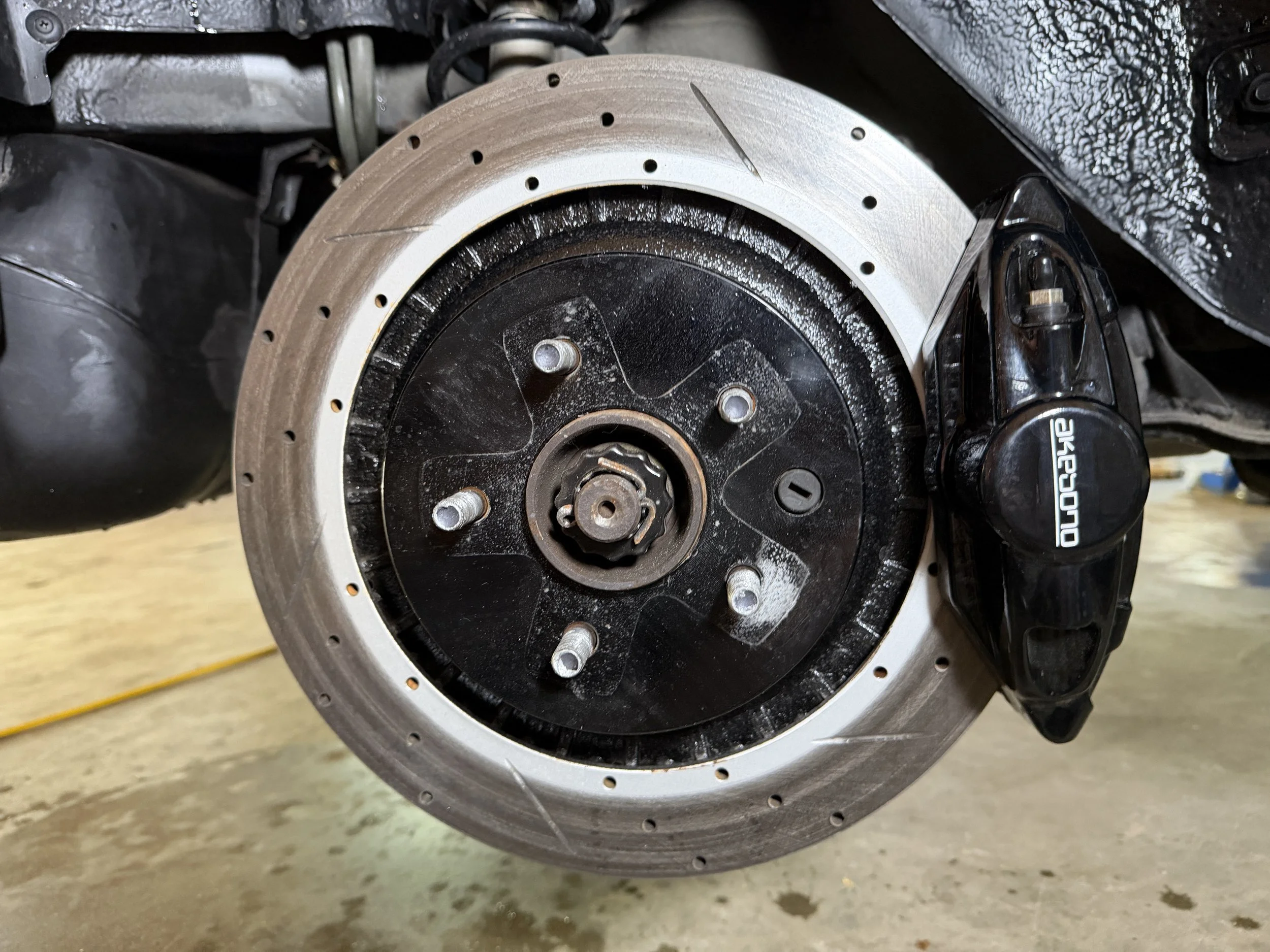 Close-up of a motorcycle wheel with the brake rotor and caliper visible, with some markings on the rotor.