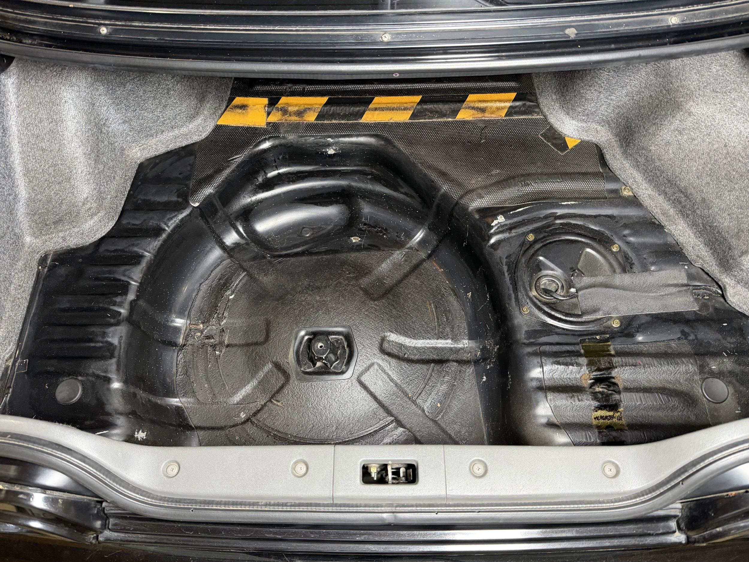 Empty car trunk with the spare tire well visible, no spare tire present, and the trunk floor exposed.