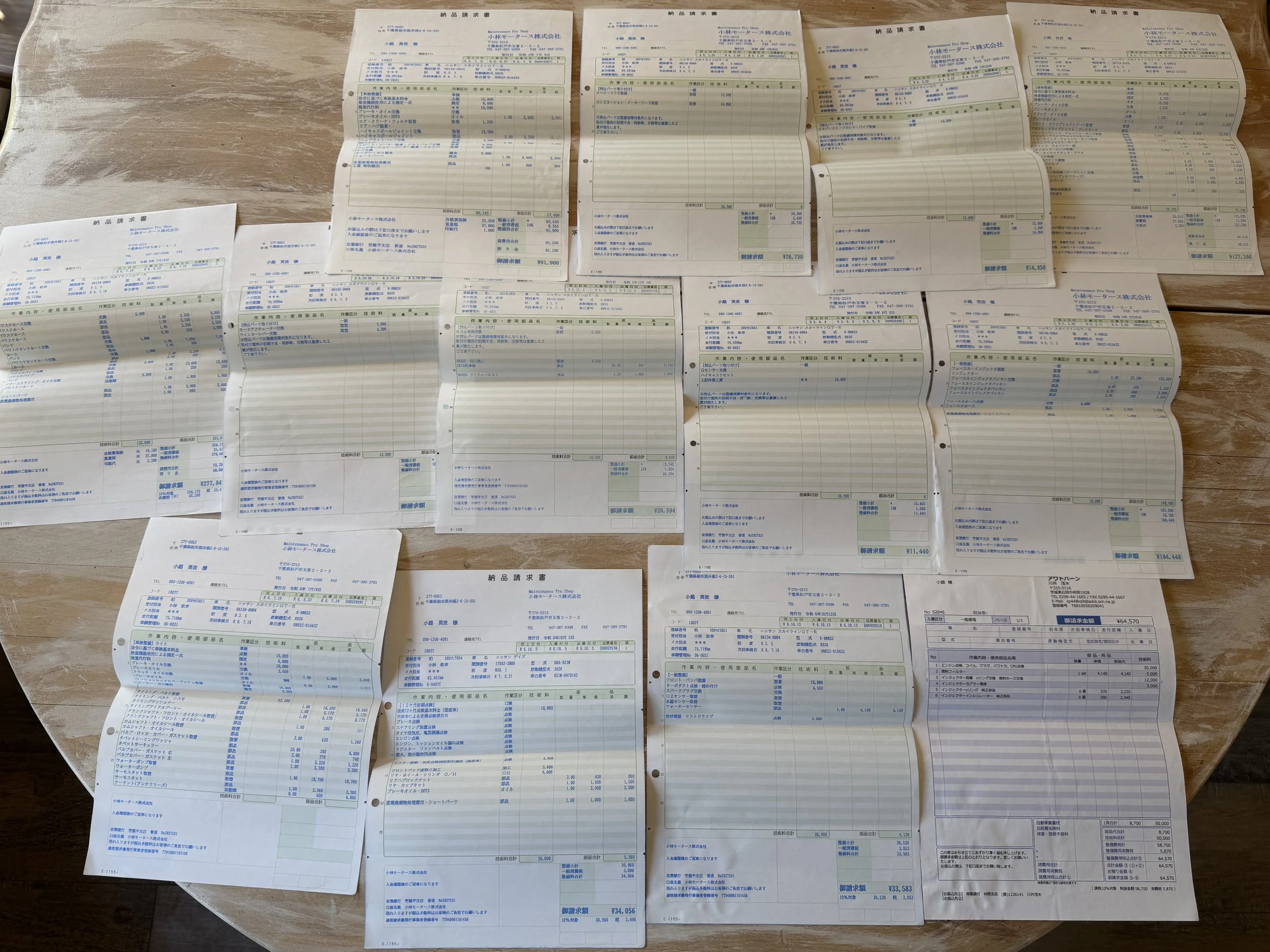 Collection of crumpled and flattened paper receipts or bills spread out on a wooden table.