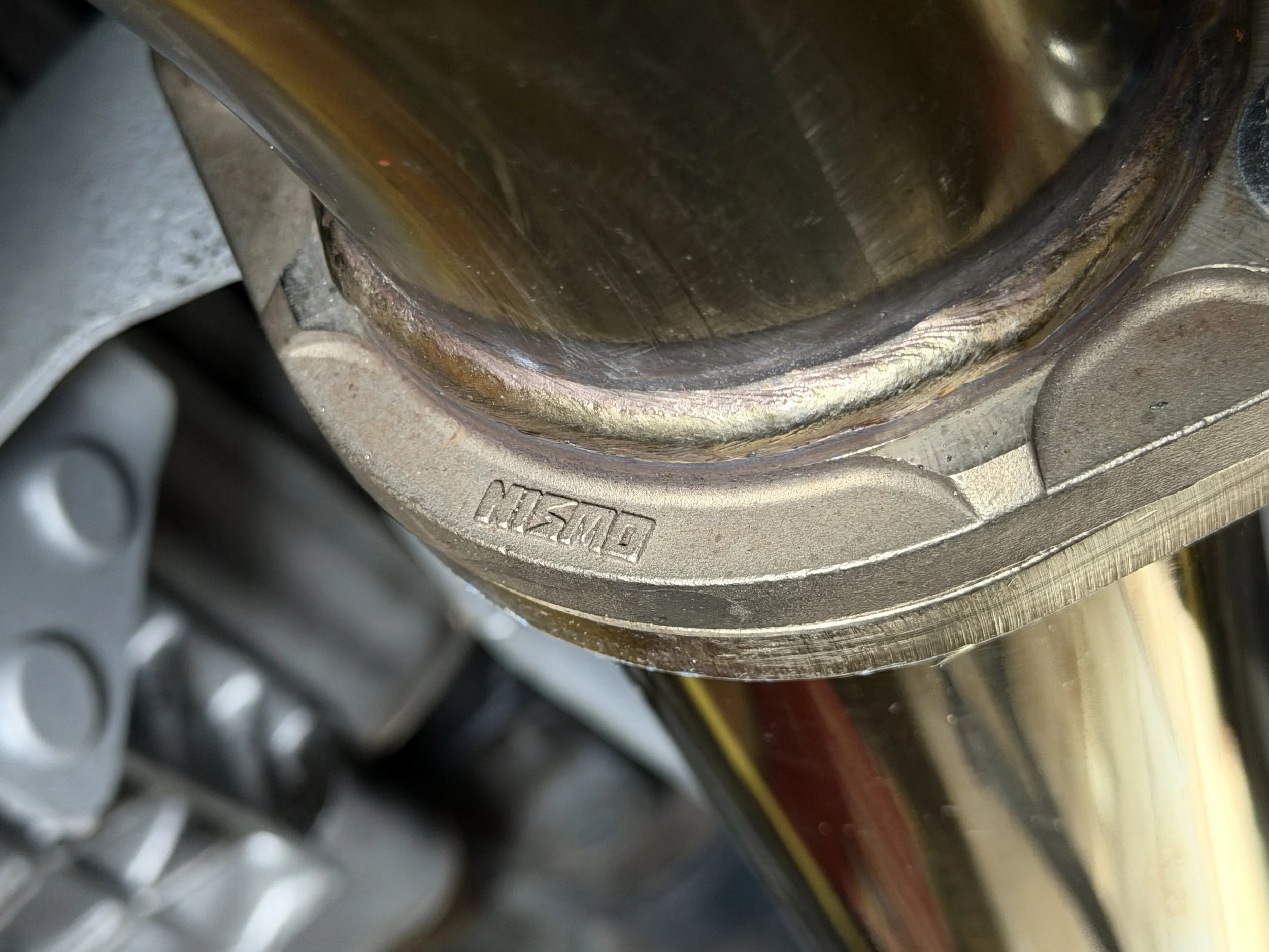 Close-up view of a motorcycle engine component with a visible 'NISSIN' engraved logo, showing metallic parts and some rust or discoloration.