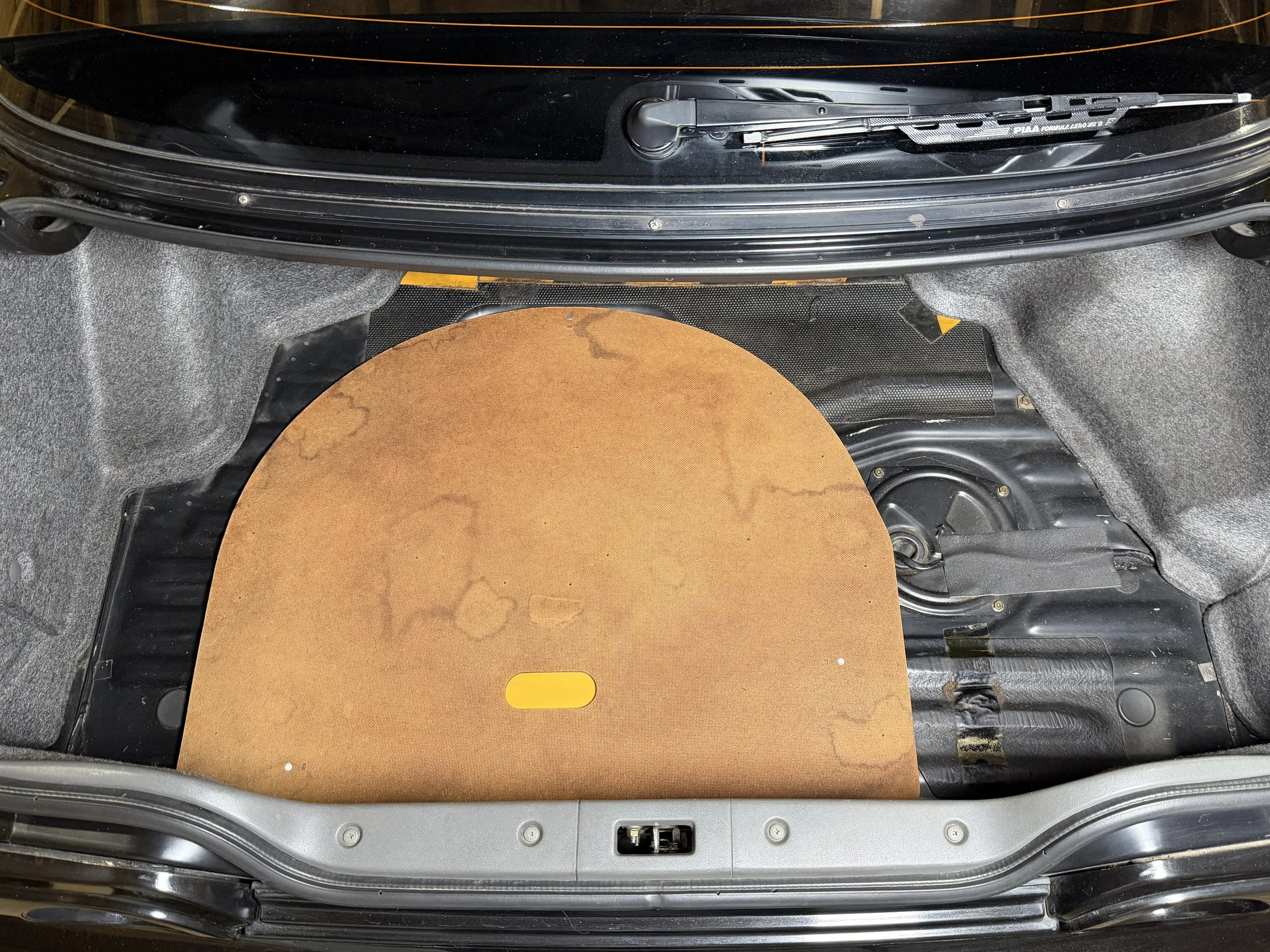 Car trunk with partially removed rear seat, exposing the metal floor and insulation padding.