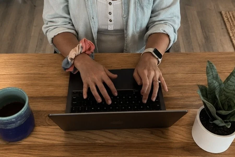 Hands working on a laptop at a desk, representing digital systems, workflows, and technology support.