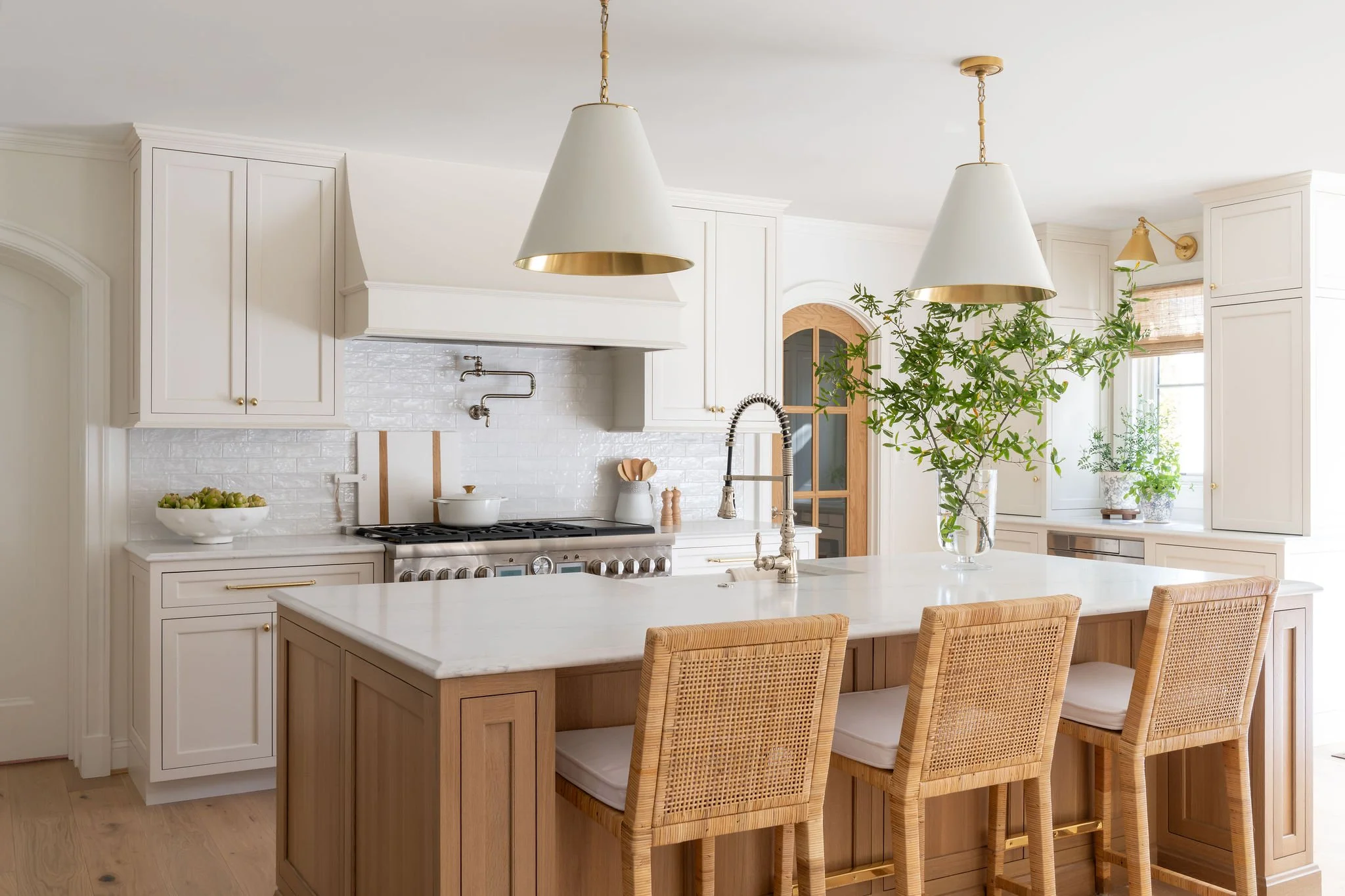 A coastal kitchen with rattan counter stools and botanical elements.