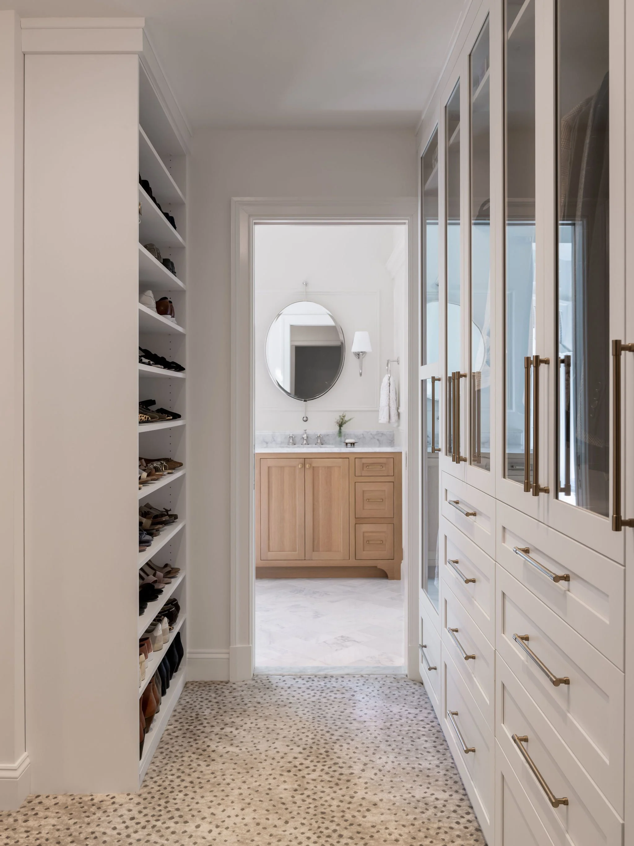 A custom closet system with animal print carpeting opening into a primary bathroom.