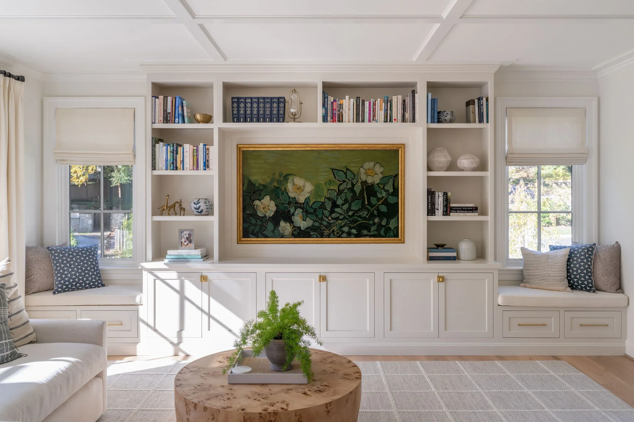 A light-drenched living room with cream built-in bookcases and trimmed ceiling detail. 