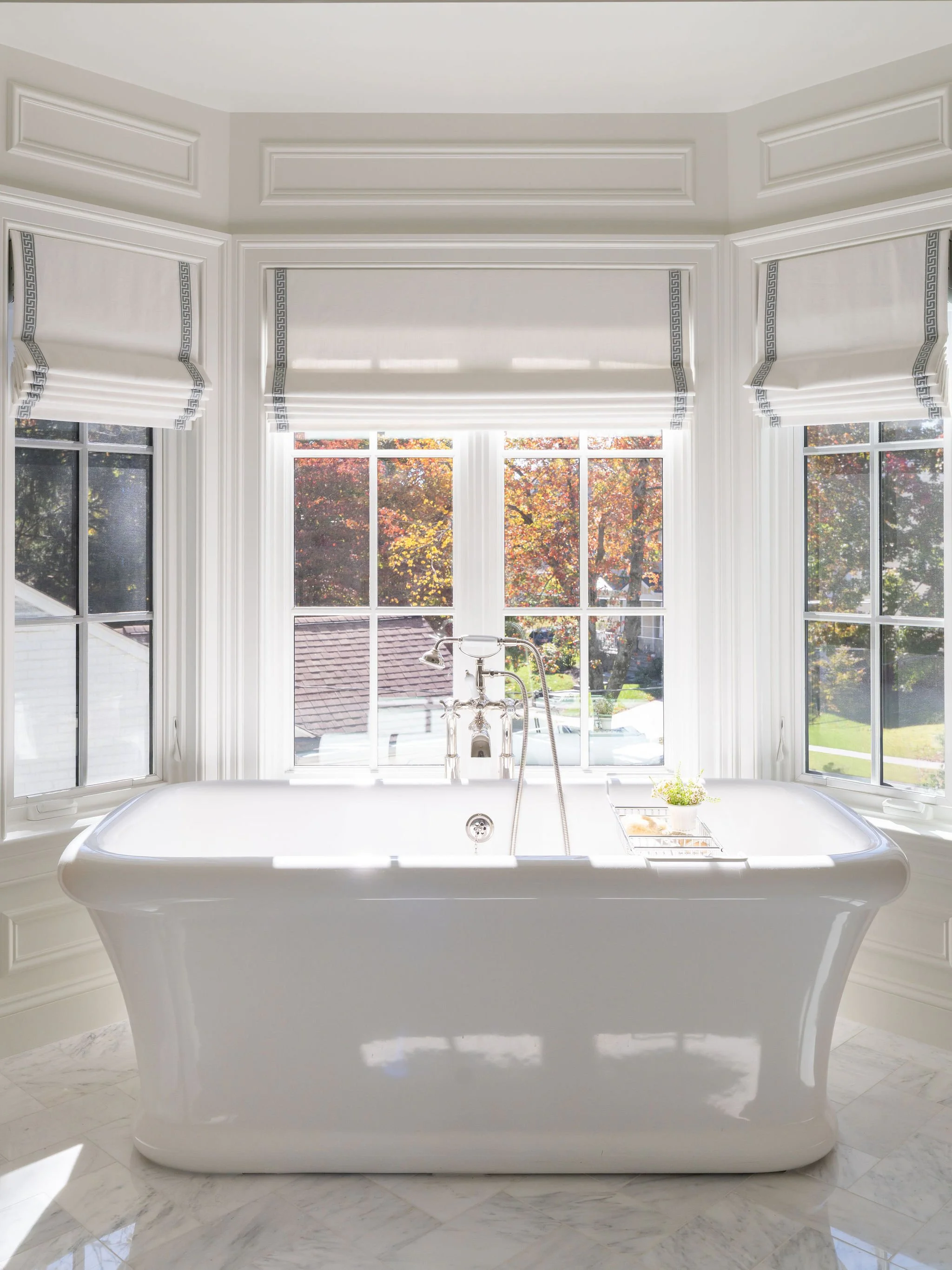A beautiful soaking tub washed with natural light from a bay window in the background.