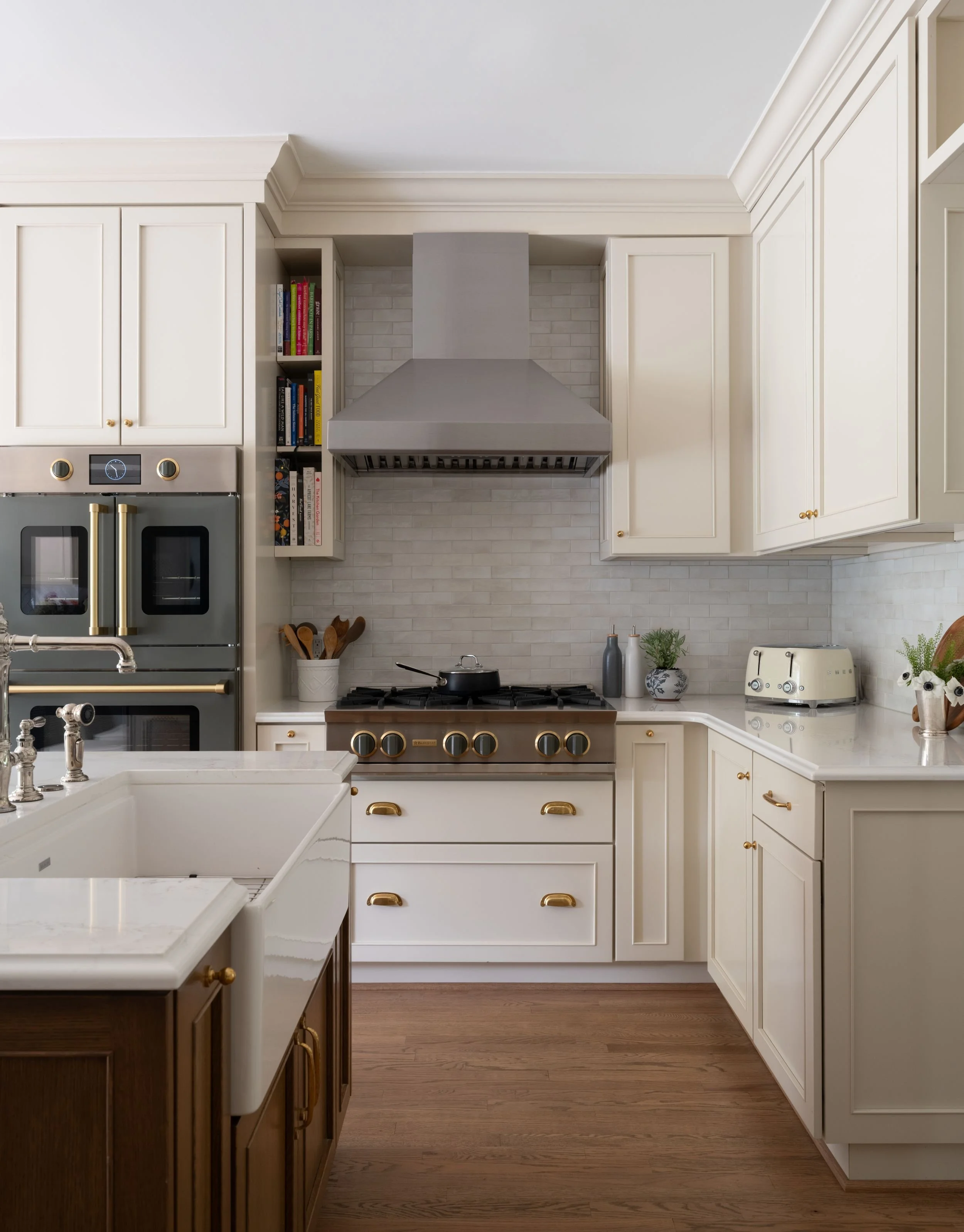Cream kitchen with warm stained island and apron-front sink, with cooktop and range hood.