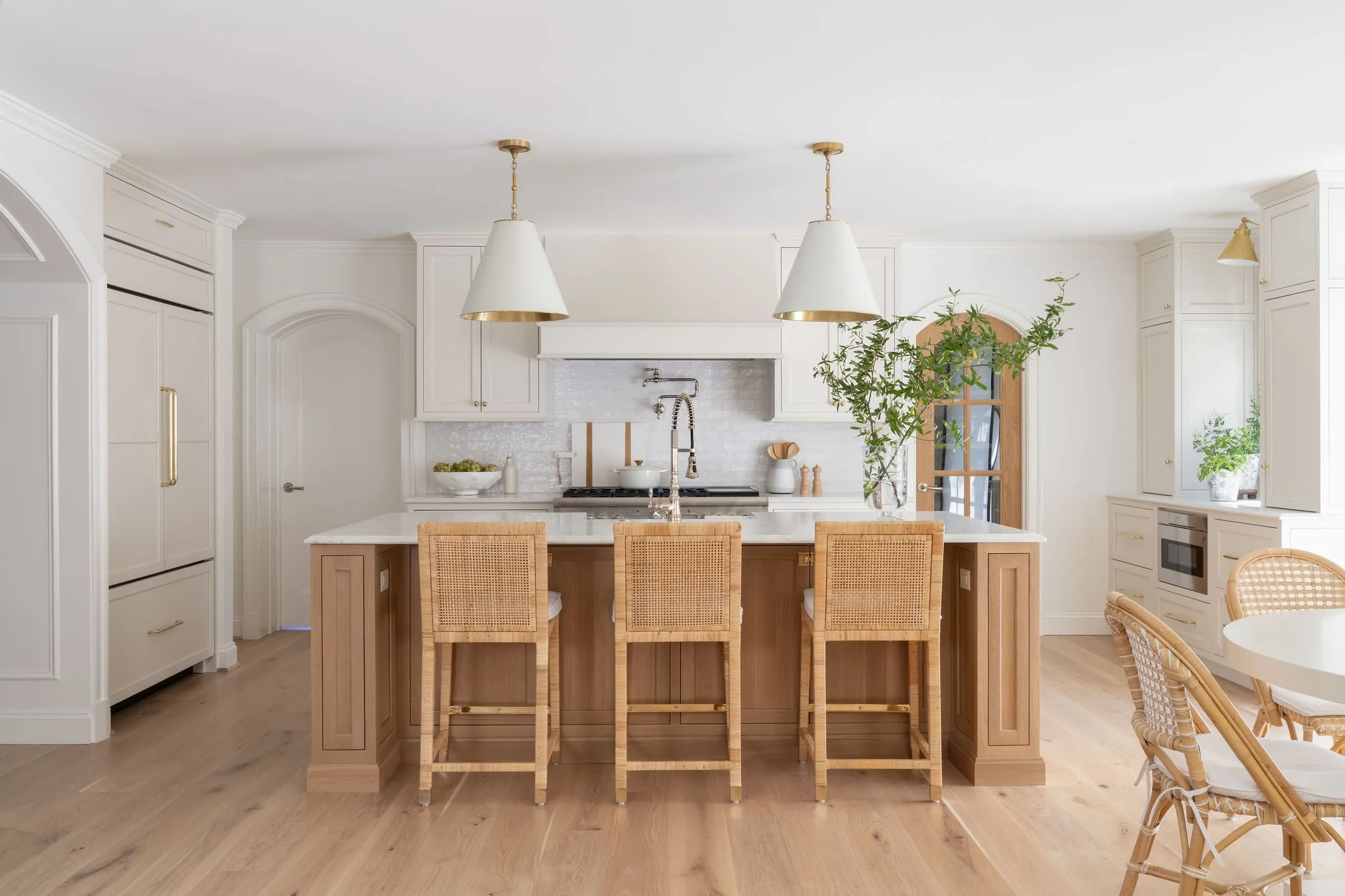 A kitchen in a neutral palette with white oak accents and coastal furnishings. 