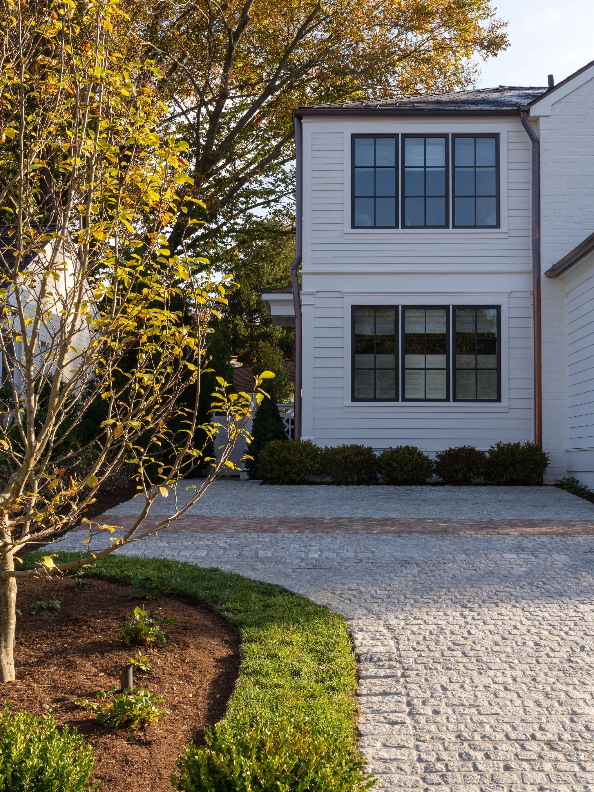 Brick and paver driveway with lush landscaping and an exterior view of the home.