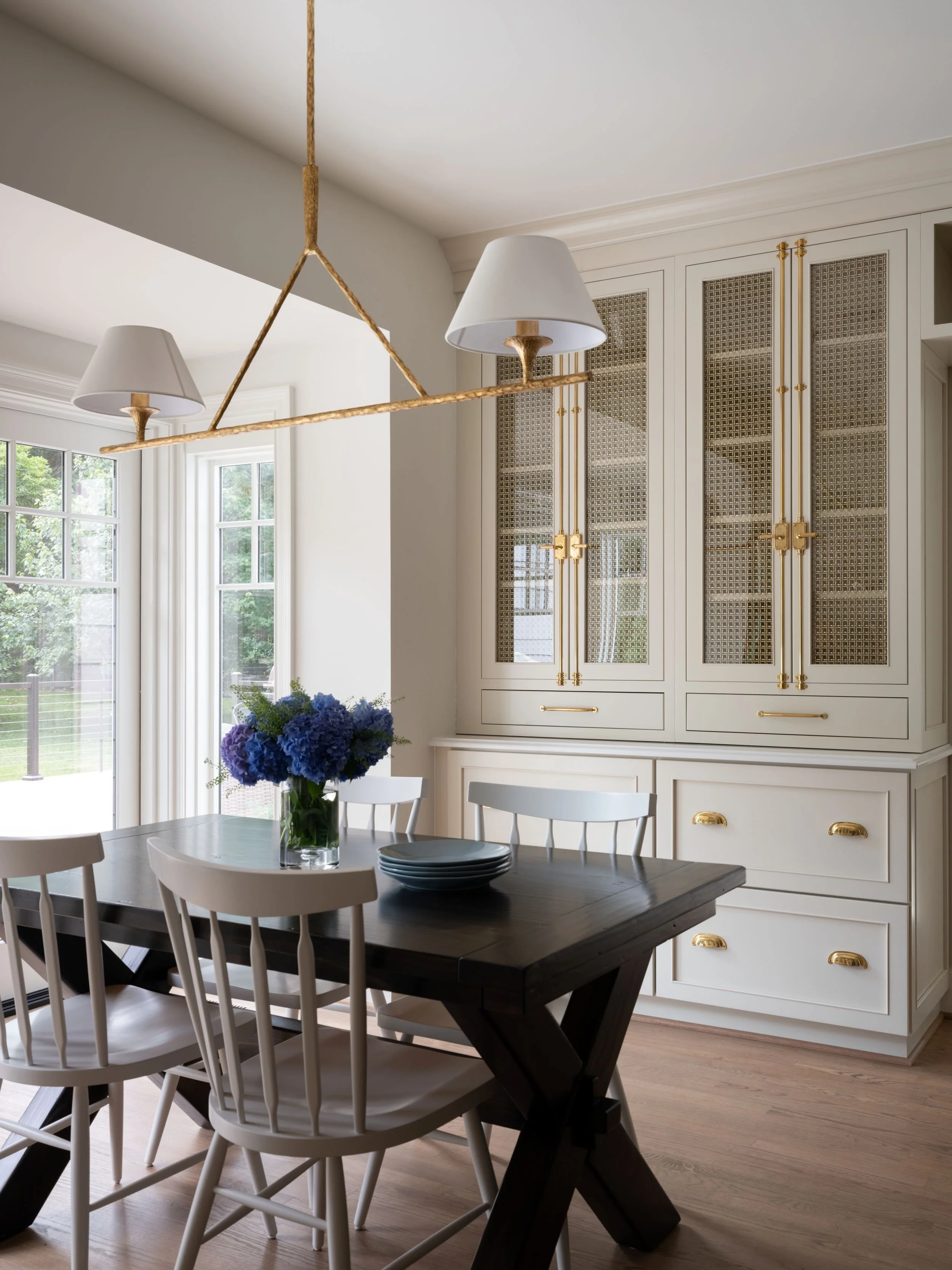 Sun-drenched dining nook with built-in hutch and decorative mesh and glass doors, and dramatic cremone bolts. 