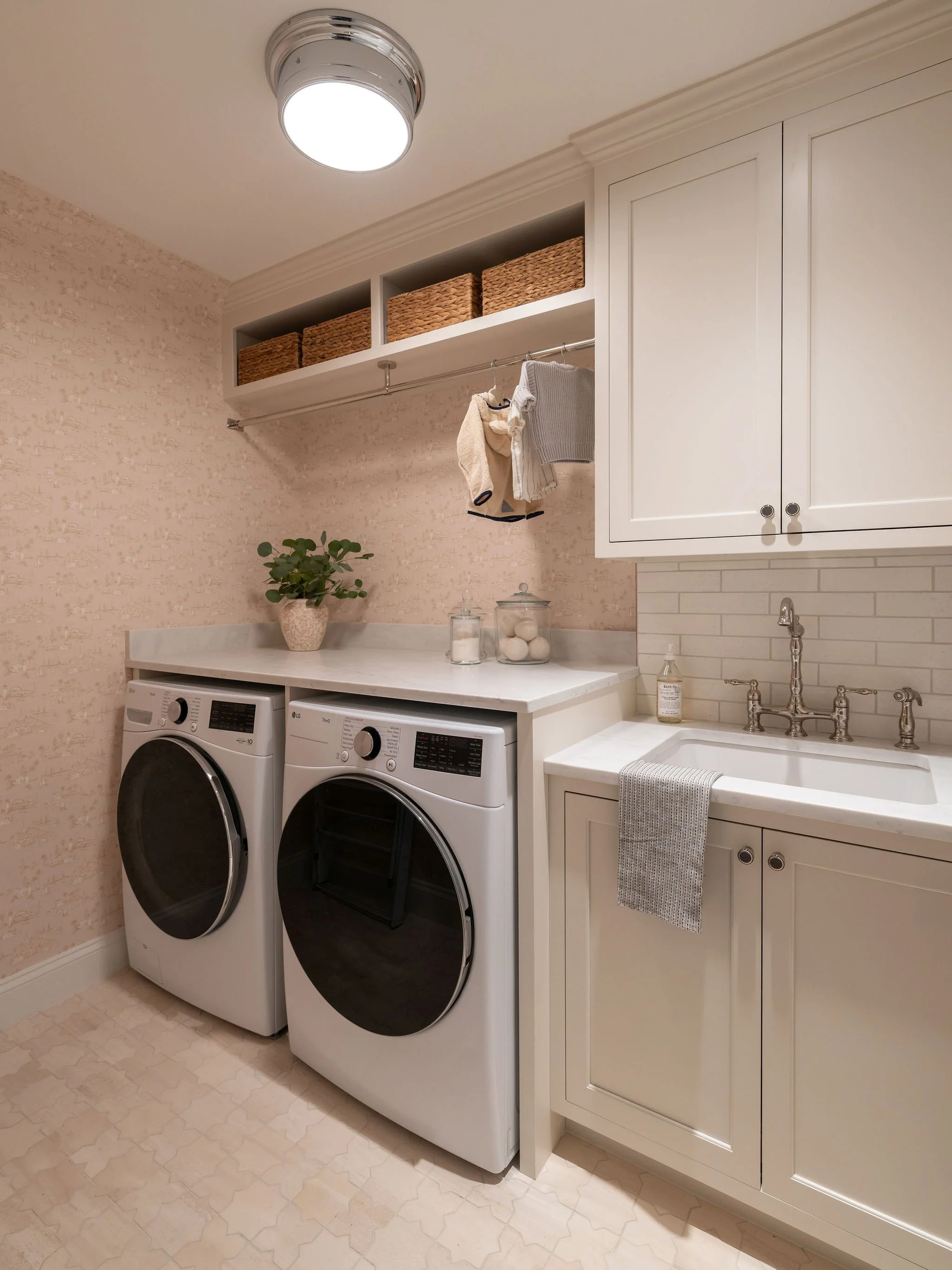 A chic laundry room with a neutral palette and playful wallpaper. 
