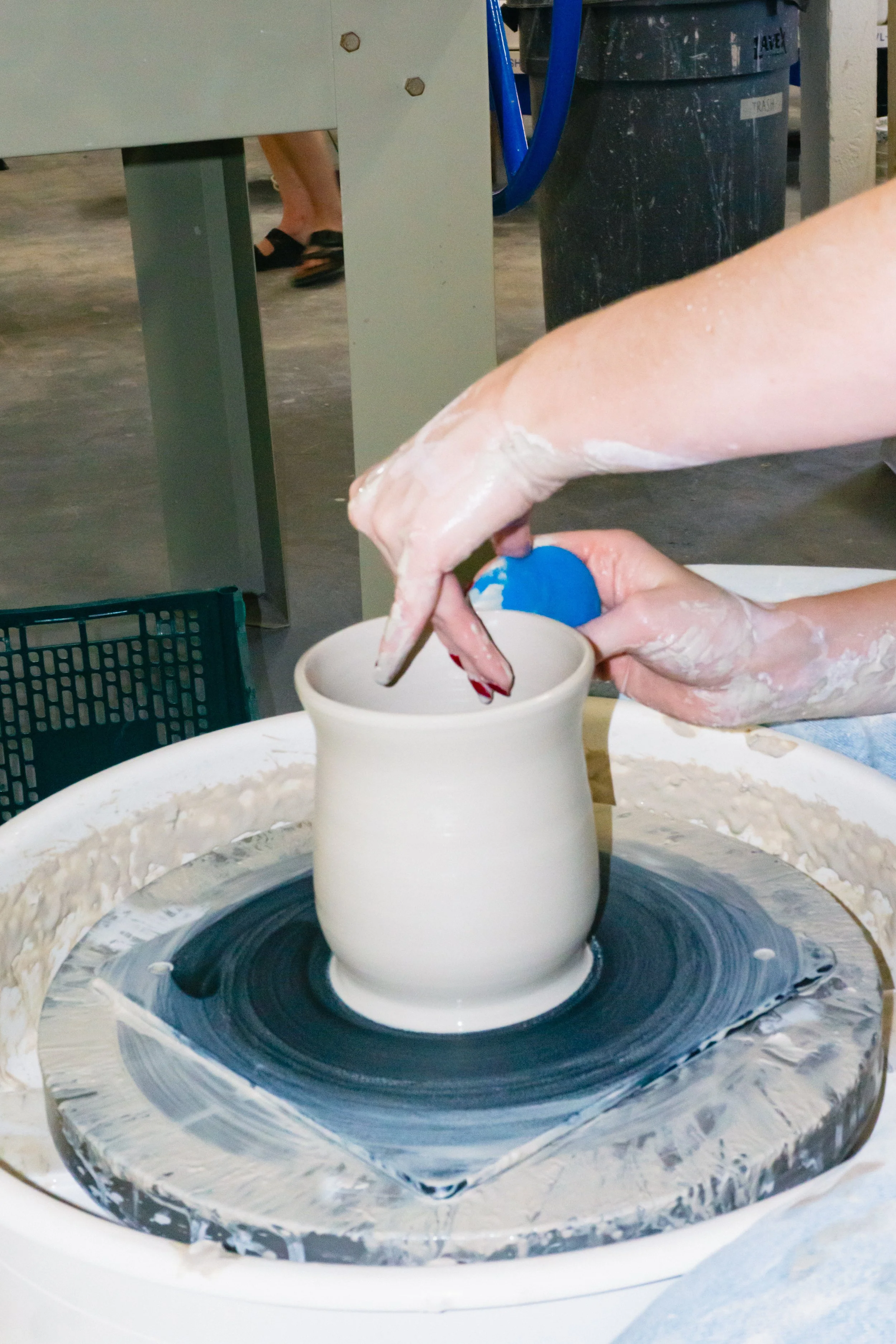 A circle with a photograph of a person doing pottery on the wheel.