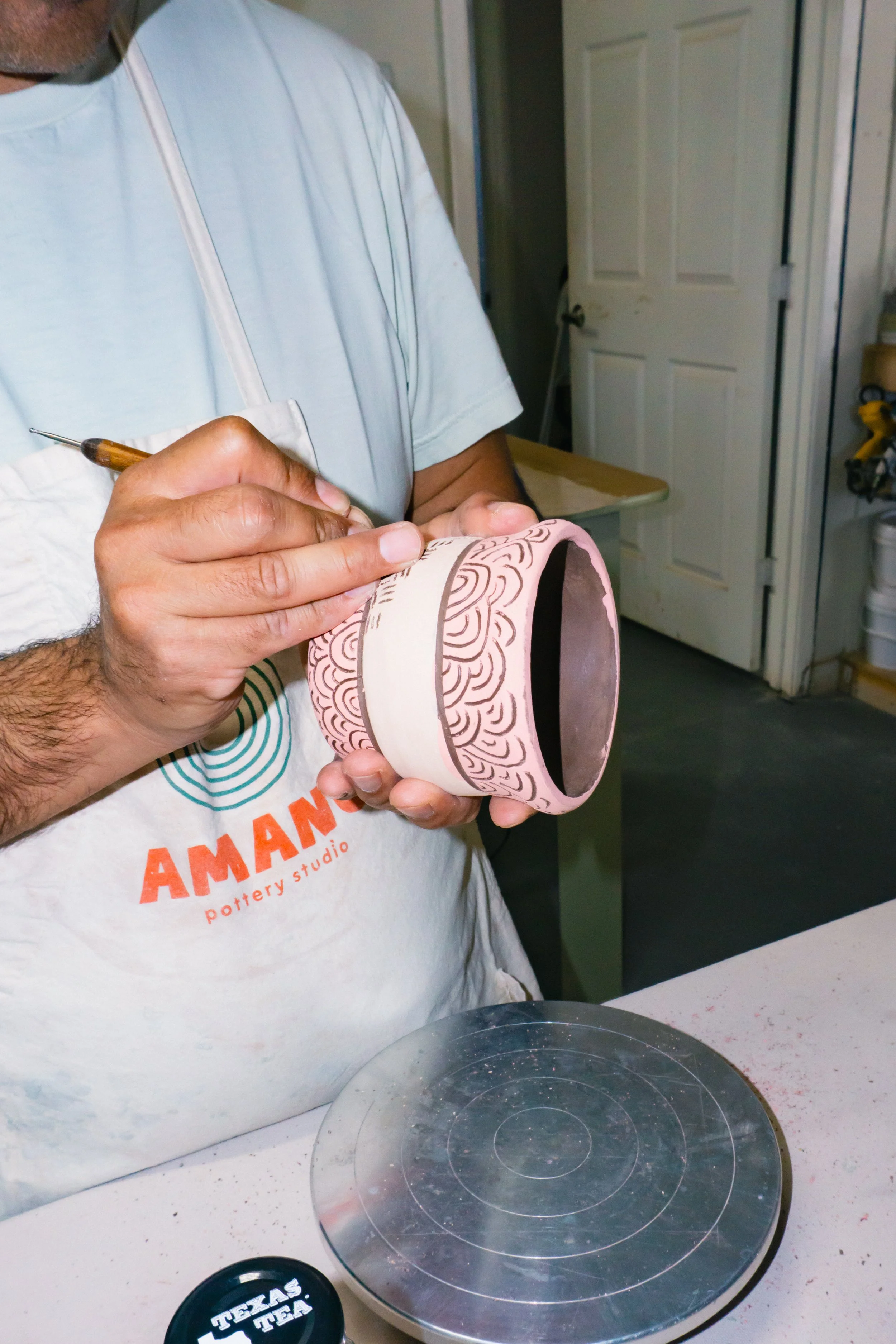 A circle with a photograph of hands playing with brown clay.