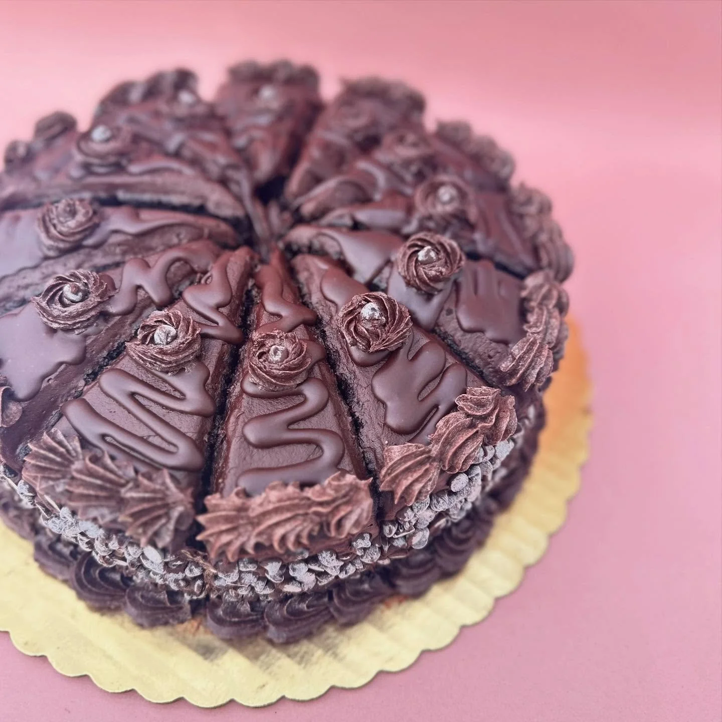 Meet the cake of the week, crafted specifically for chocolate enthusiasts! Indulge in our chocolate cake smothered in chocolate icing, topped with chocolate ganache and mini chips. Available in slices, 6&quot; cakes, and gluten-free cupcakes.