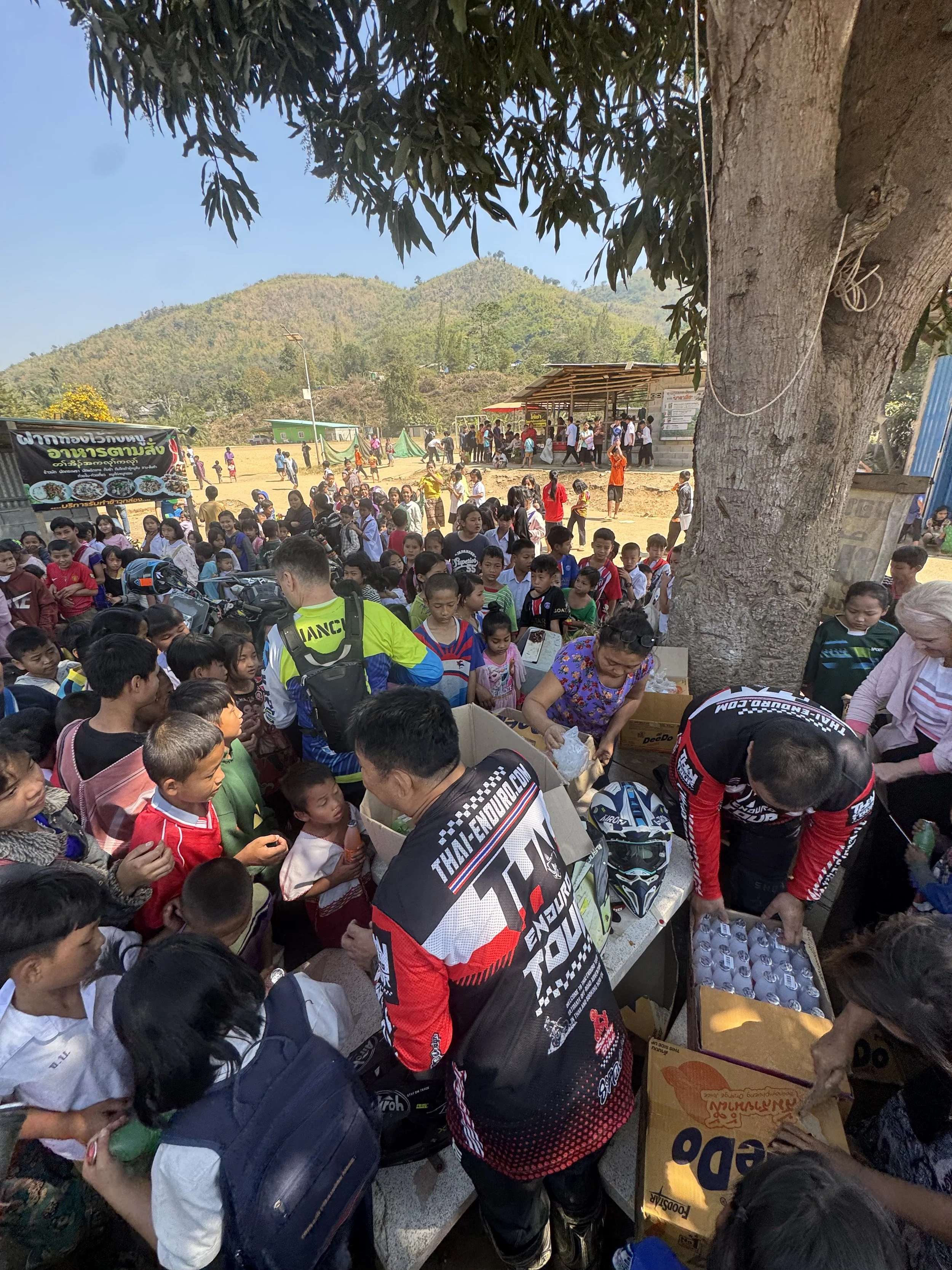 Enduro Tour Thailand charity stop – riders giving supplies to children and families in rural Thai village