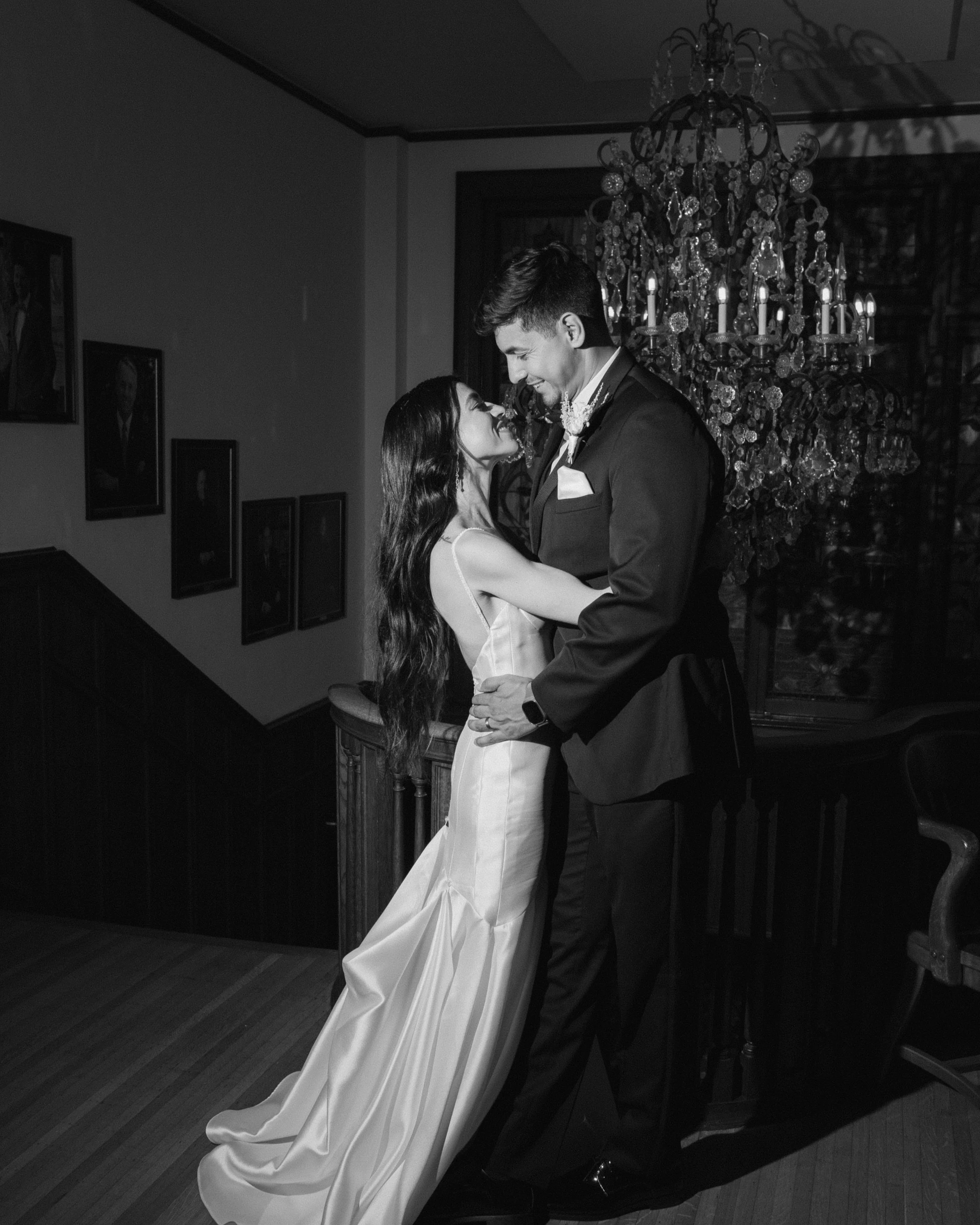 Bride and groom in wedding attire sharing a dance in a dimly lit room with a chandelier overhead. Link Lee Mansion. Houston Heights wedding by Blush Your Heart Wedding Company. Wedding planner in Houston.