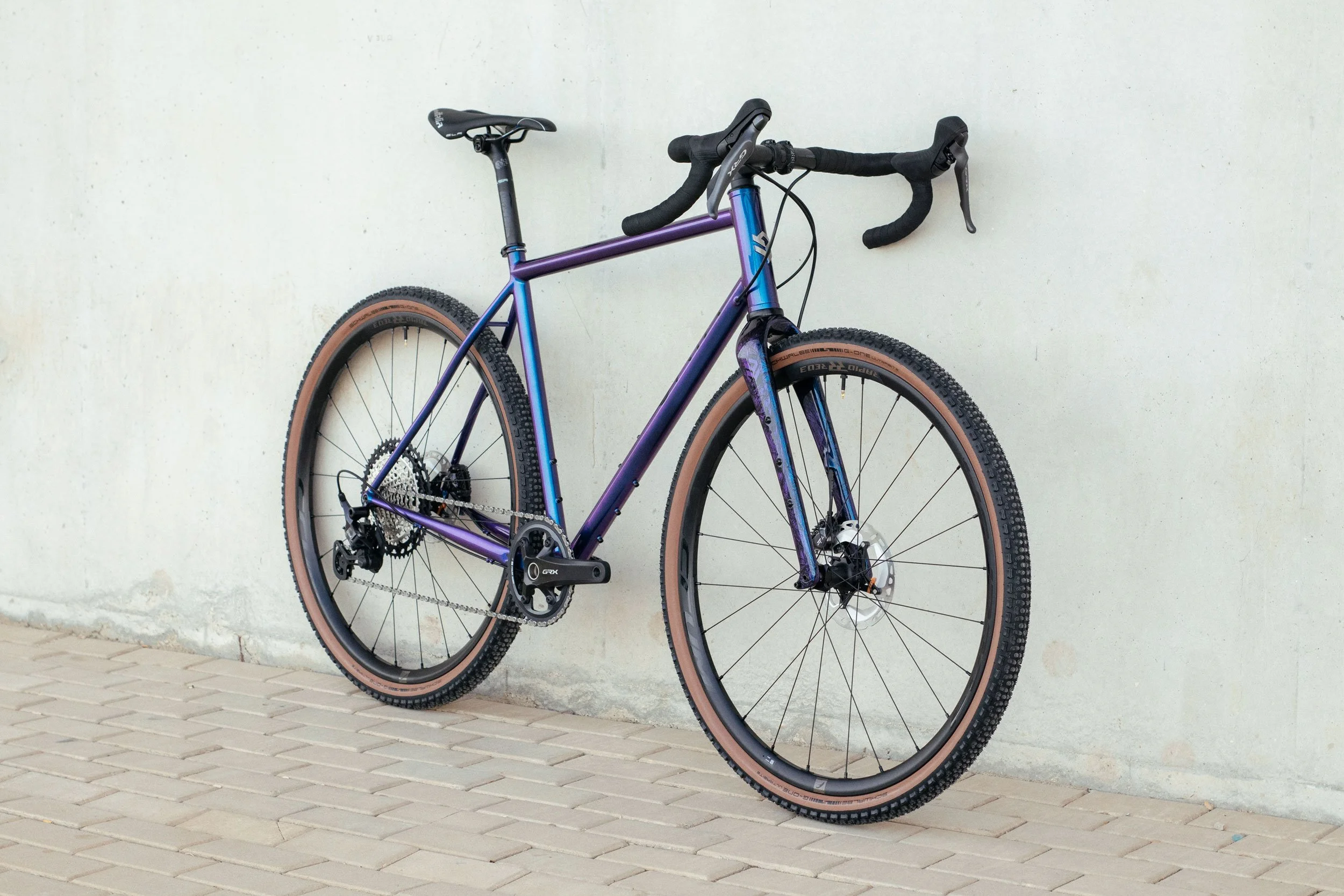 Bespoke gravel bicycle with a purple frame, featured in the OXIA brand identity project.