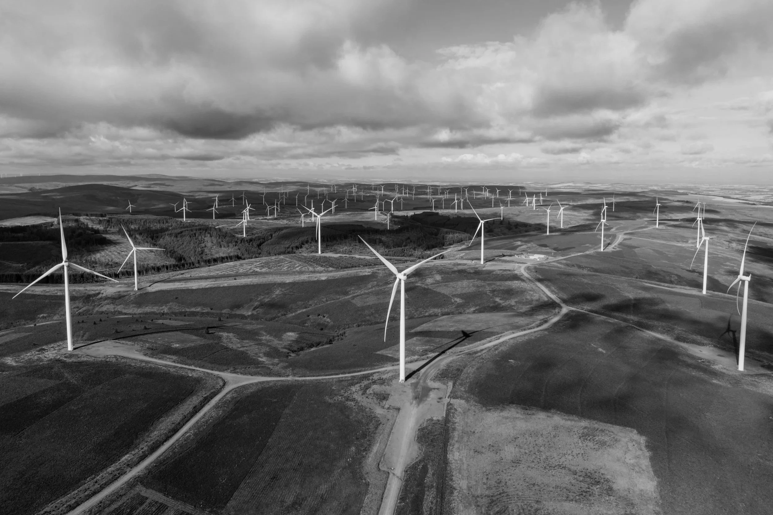 Aerial view of numerous wind turbines in a wind farm on a cloudy day.