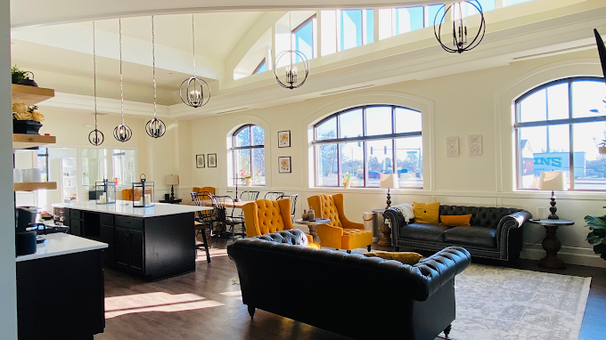Bright, spacious living room with large windows, black and yellow sofas, modern chandelier lighting, and a kitchen area with island, located in Burr Ridge, IL