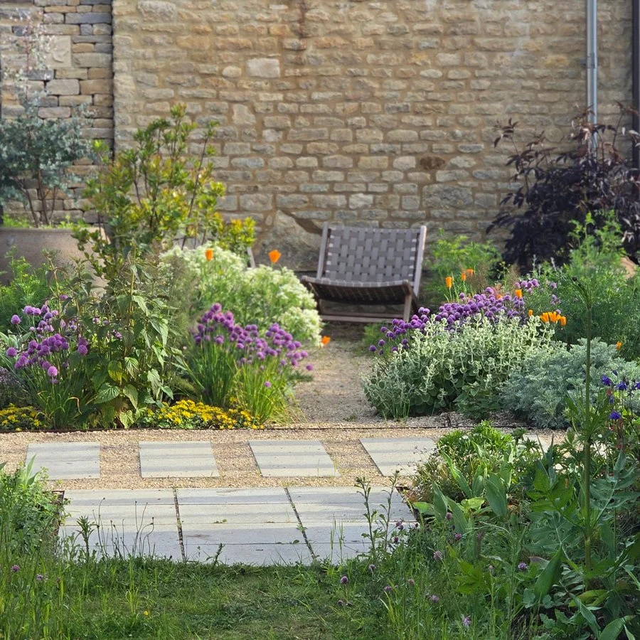a garden chair in a gravel garden with bright flowers