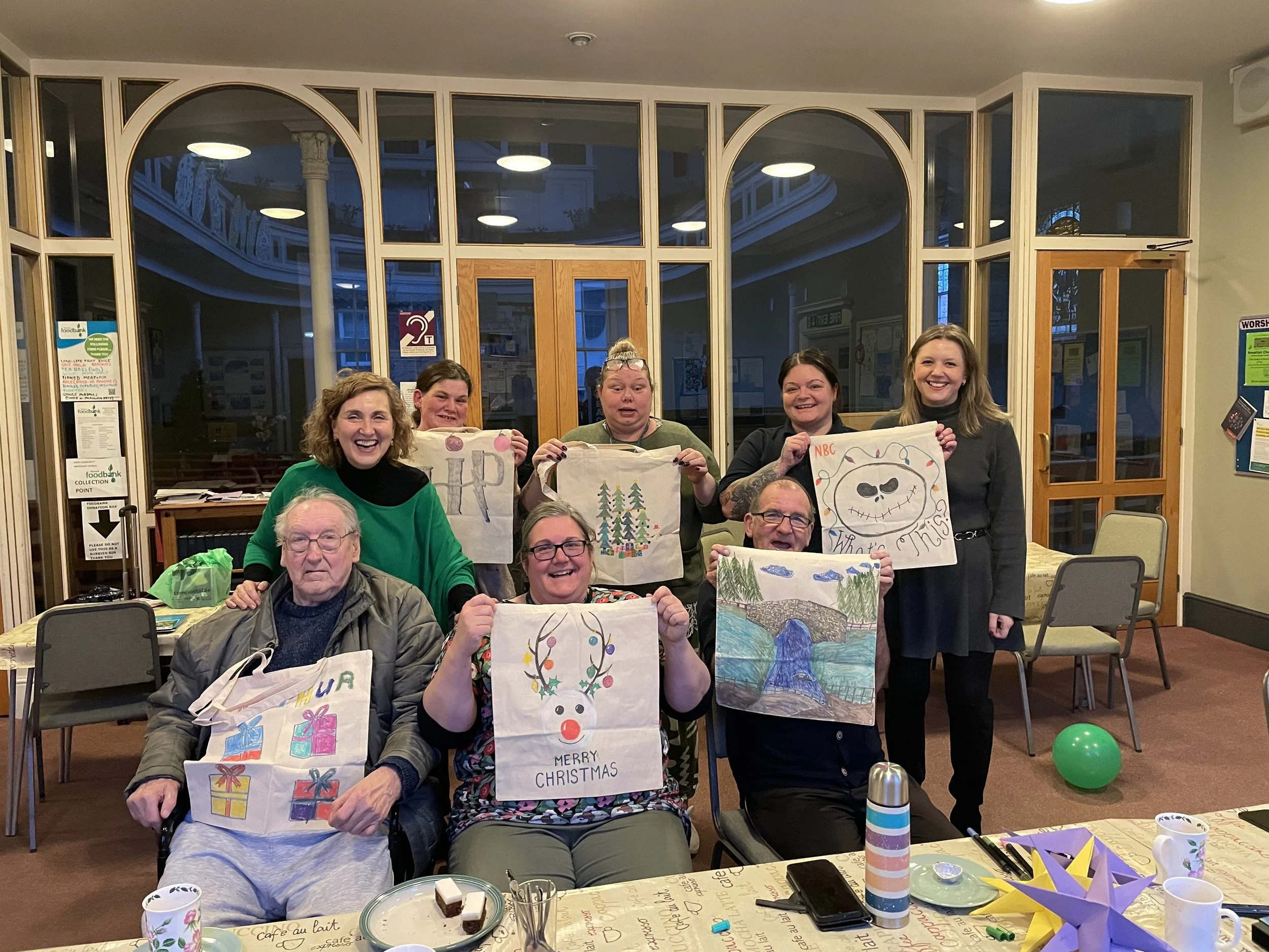 A group of adults smiling at the camera holding up their art work