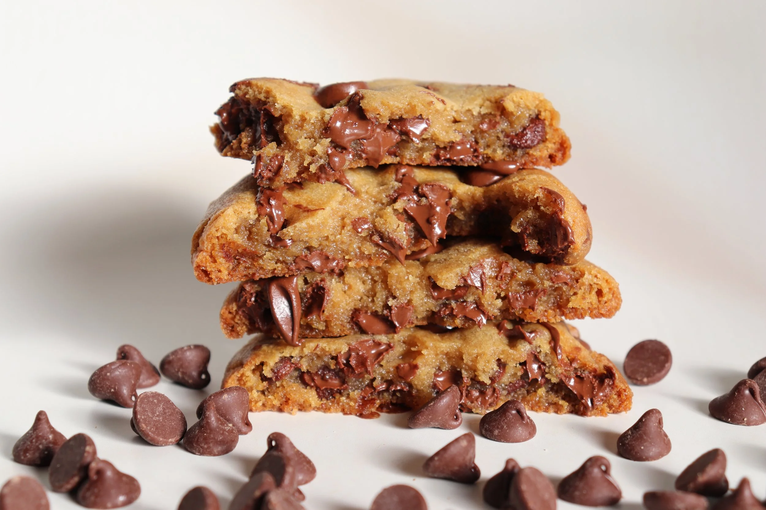 A stack of four colorful sprinkled cookies on white fabric background.
