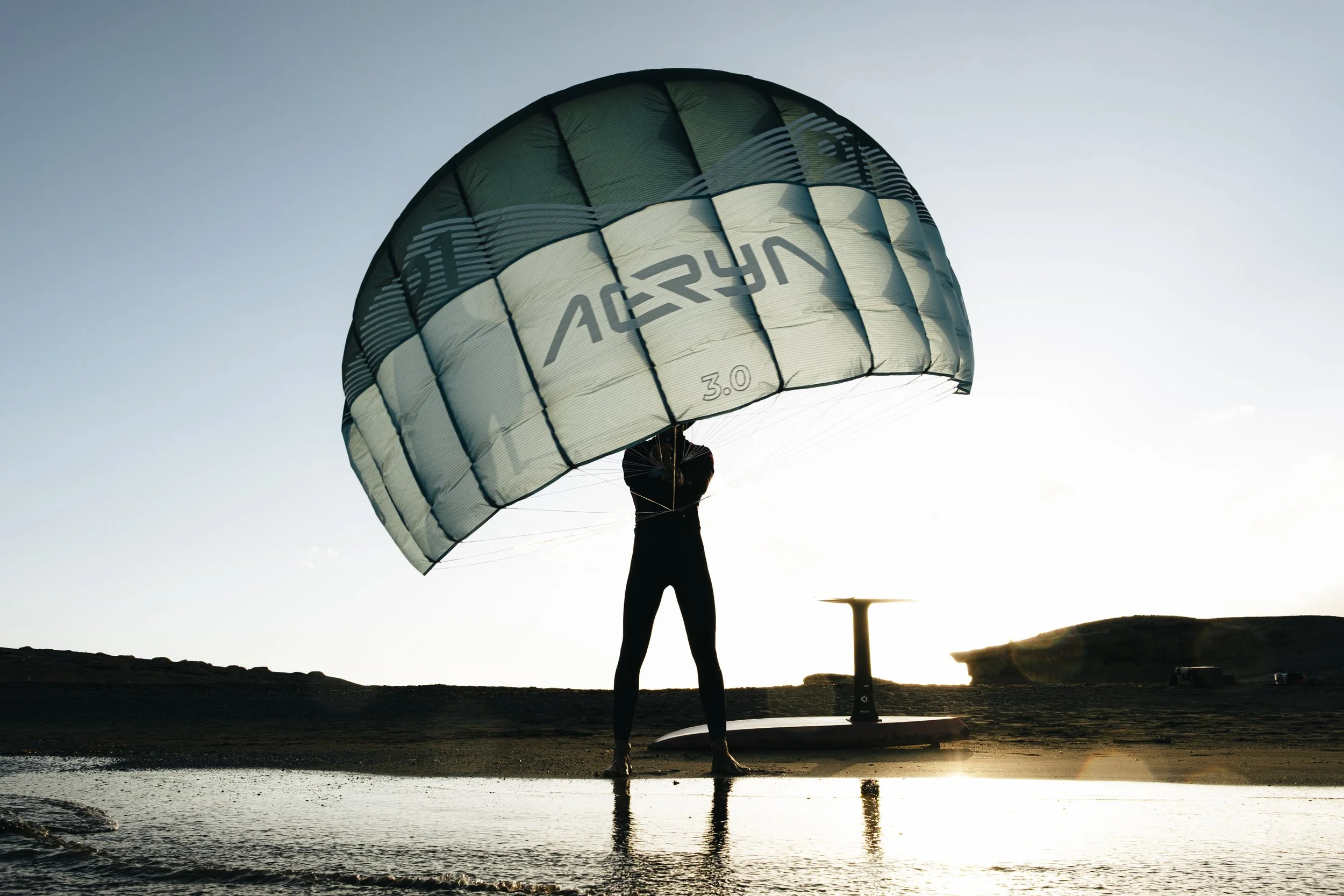 Rider using Aeryn parawing on foil board riding small waves in the ocean