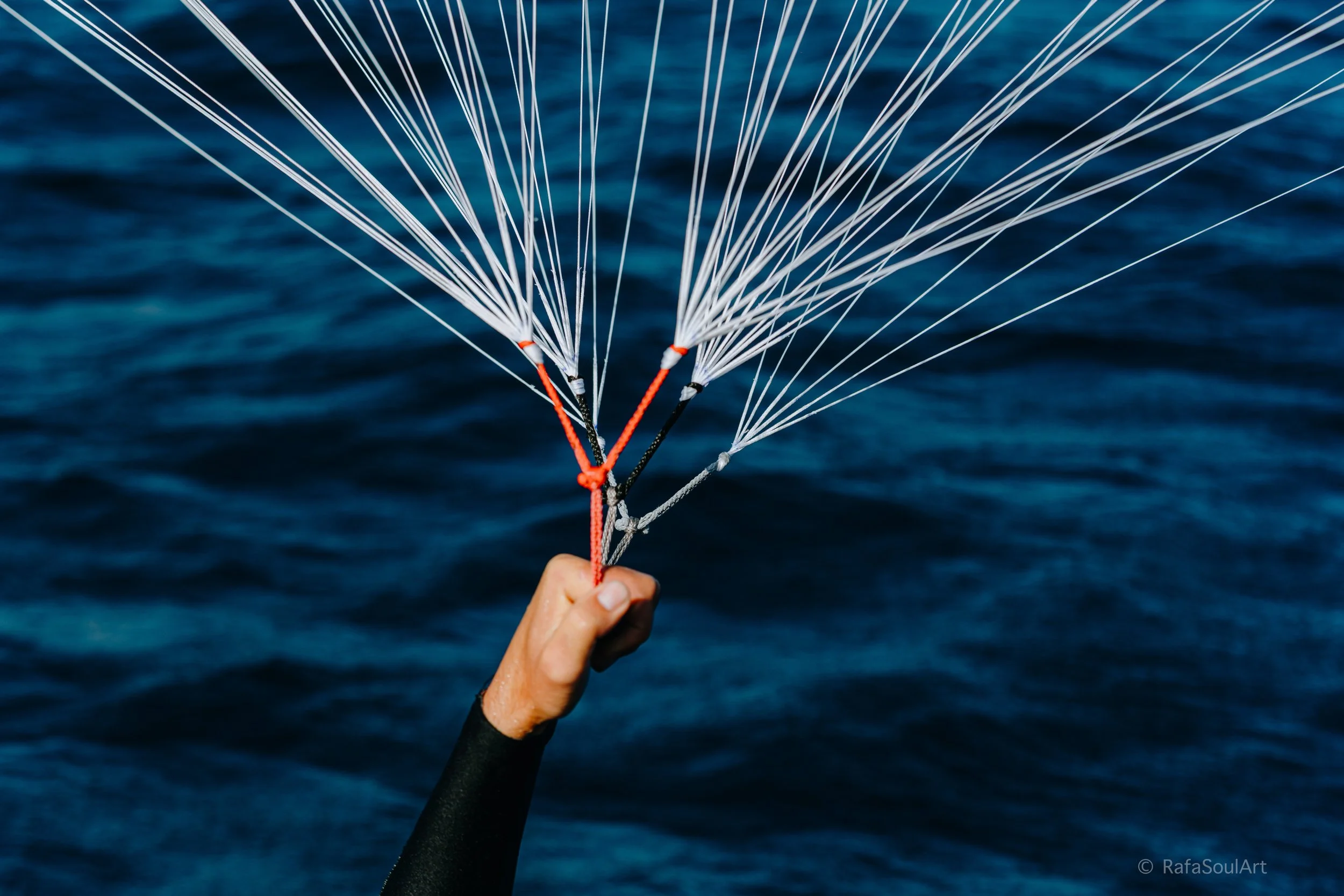 Close up detail of parawing lines and control system in hand over the ocean