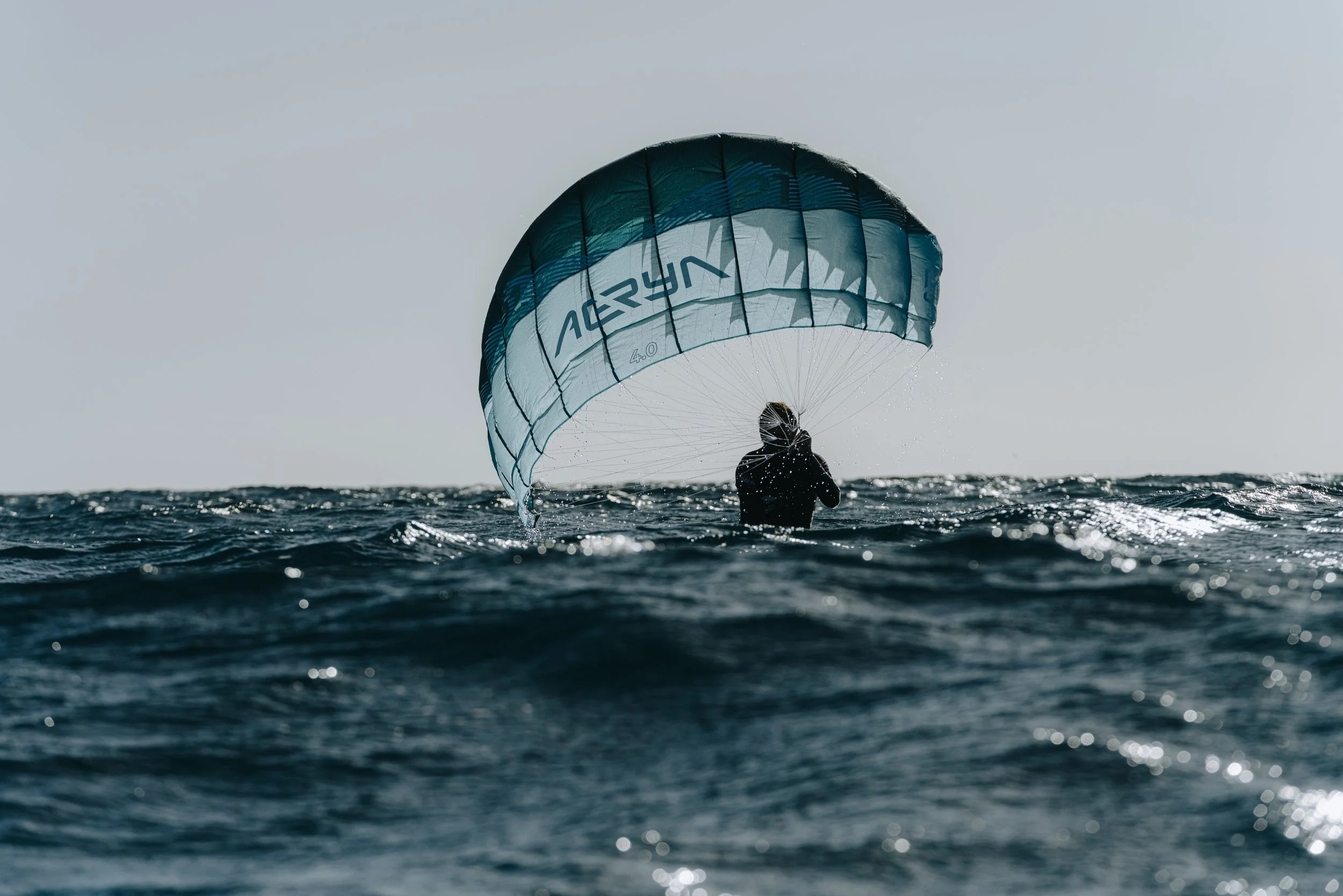 Rider using Aeryn parawing on foil board riding small waves in the ocean
