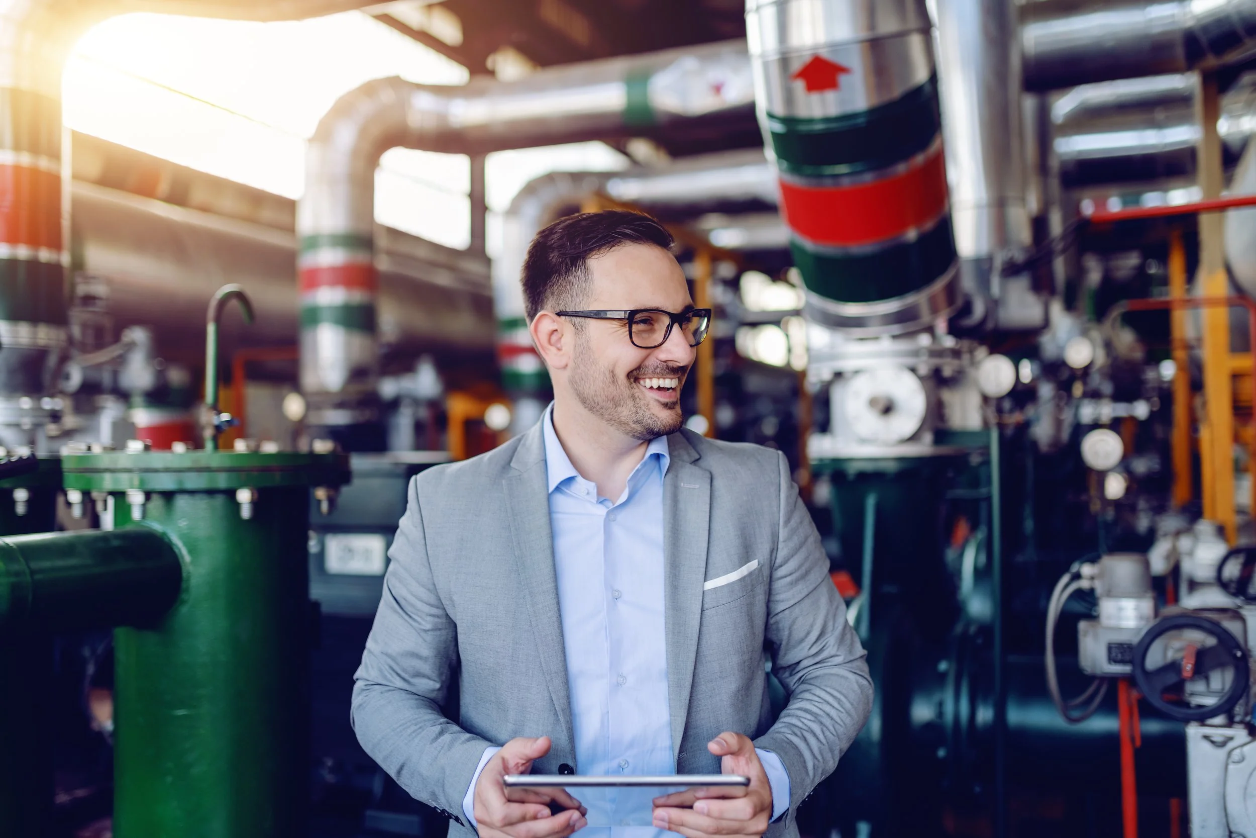Energy auditor with tablet inside an industrial facility assessing machinery for efficiency improvements