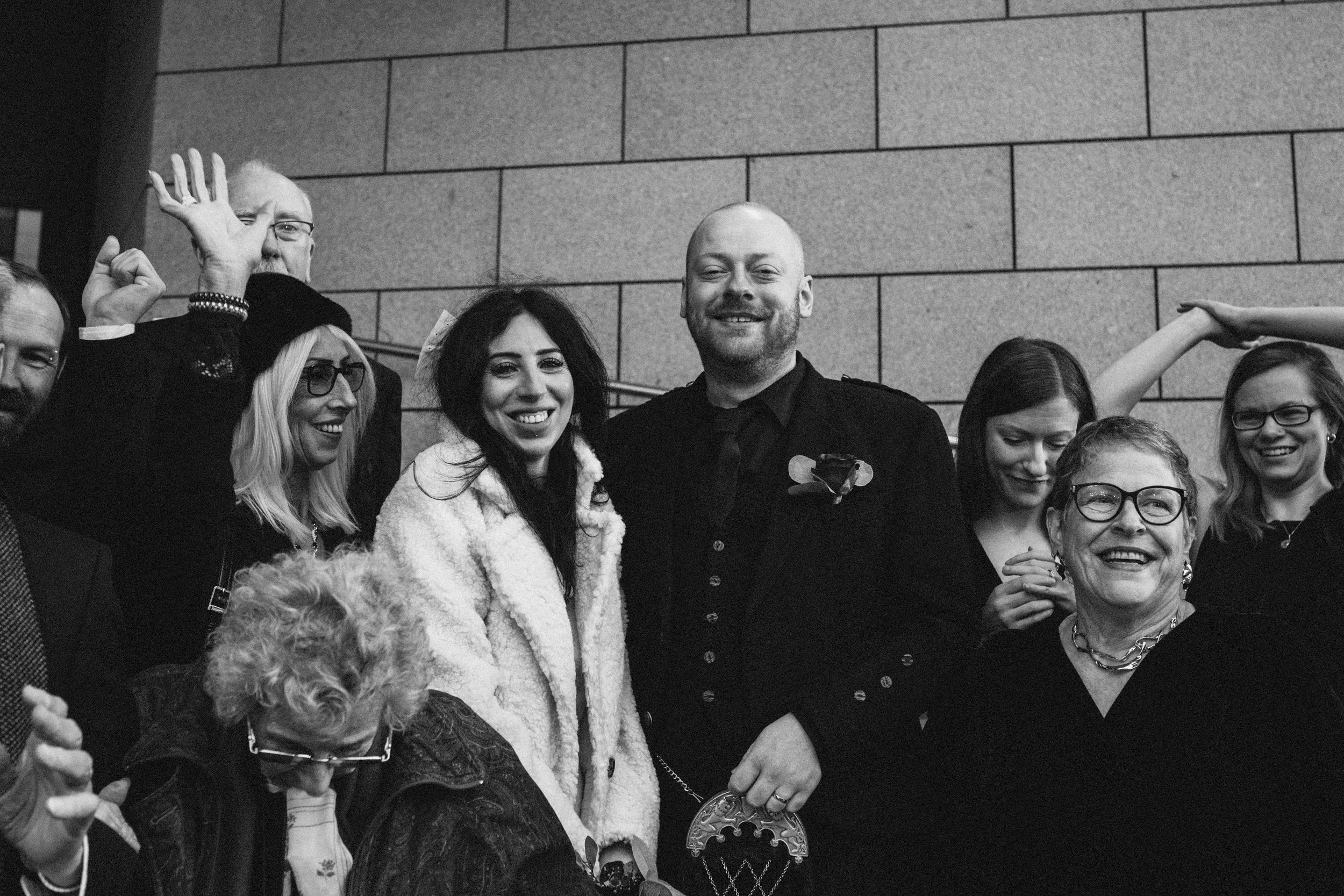 Group of smiling people at a celebration, one person dressed as a police officer with a badge, black and white photo.