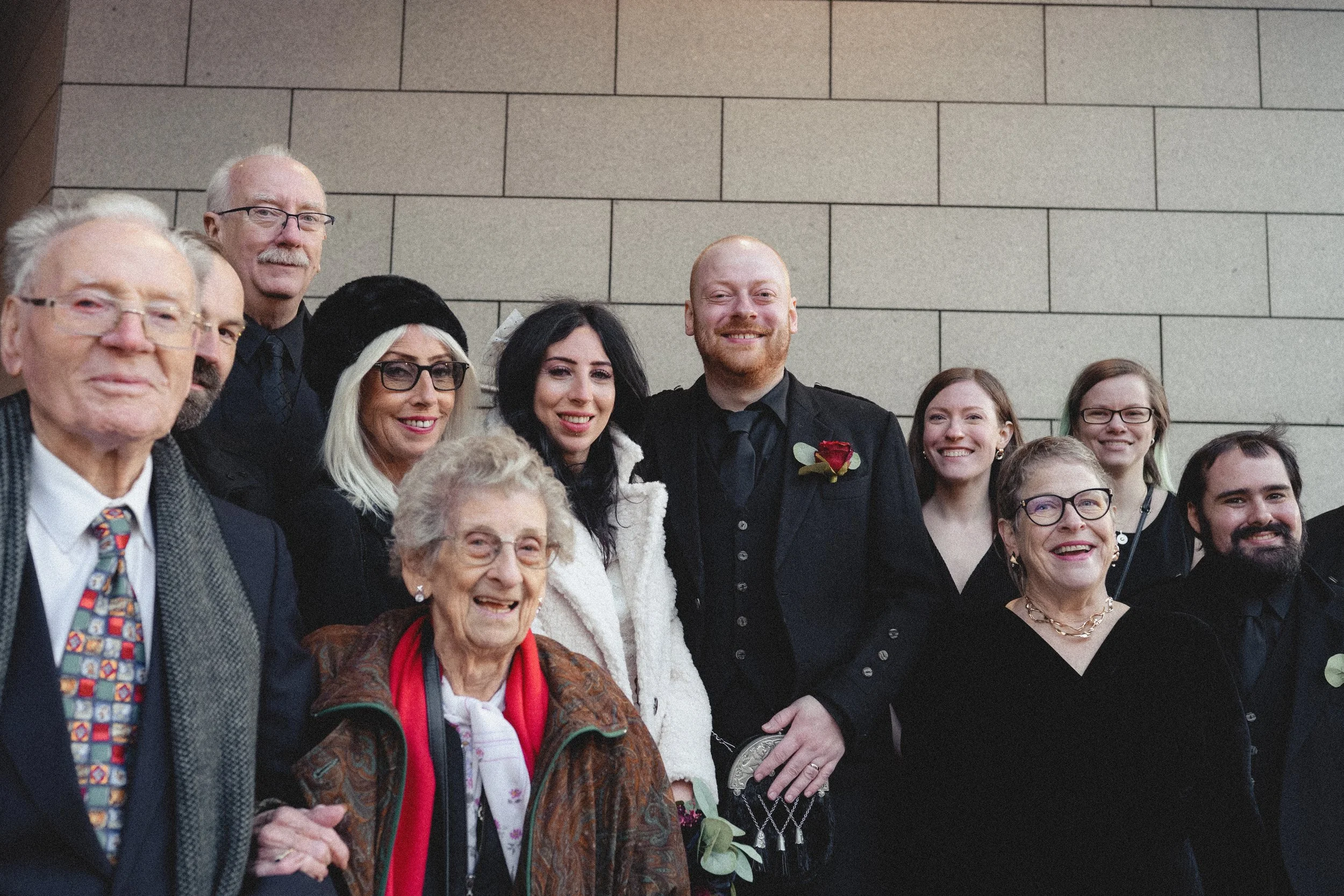 A group of people, including a bride and groom, posing for a photo at a wedding reception.