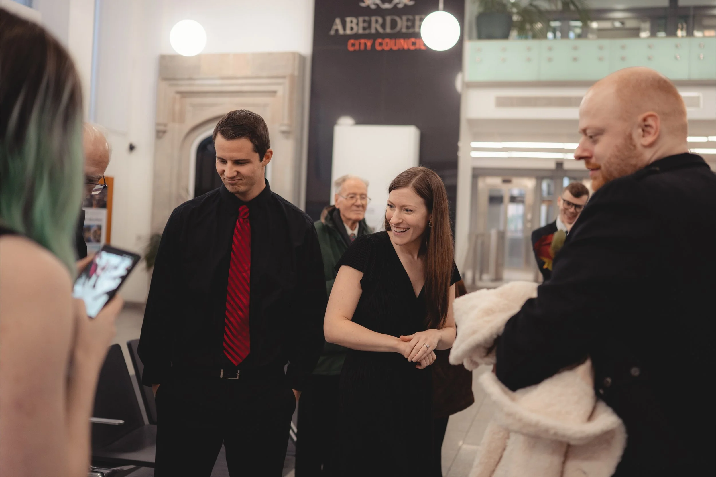 A group of people at an indoor gathering, with a sign in the background reading 'Aberdeen City Council'.
