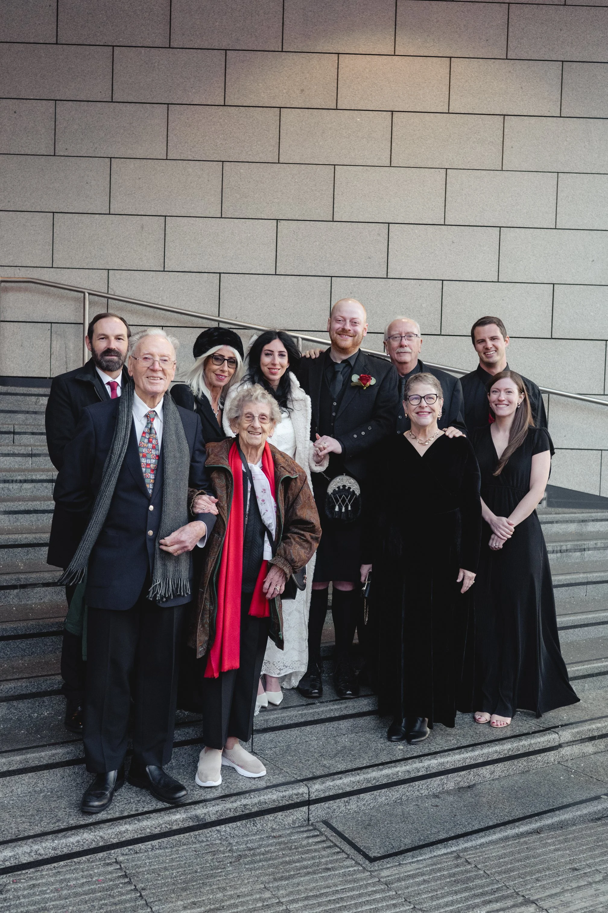 Group of ten people standing on stairs outdoors, dressed formally, smiling for a photo.