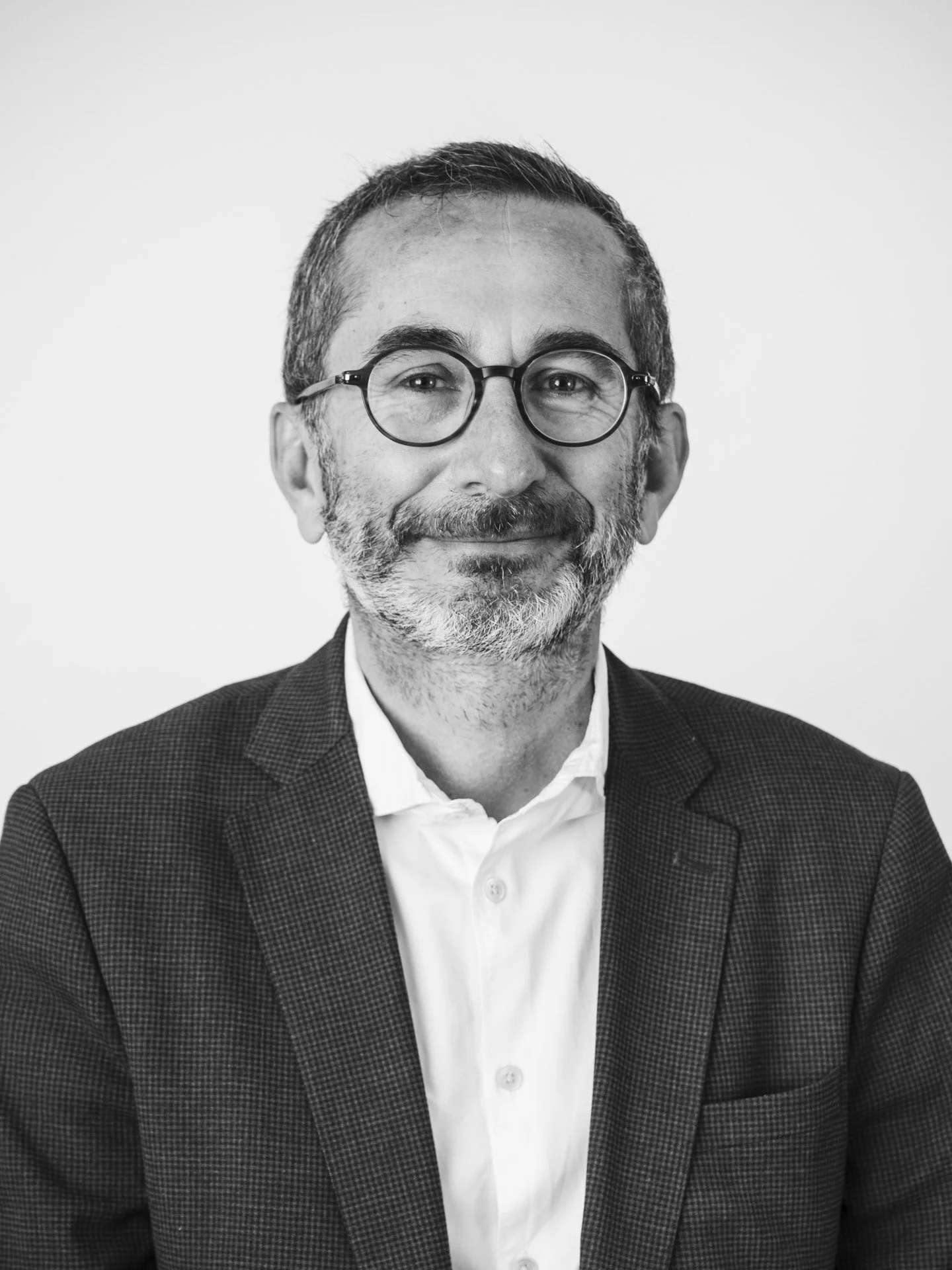 Portrait en noir et blanc d'un homme d'âge moyen portant des lunettes, une barbe et un costume.