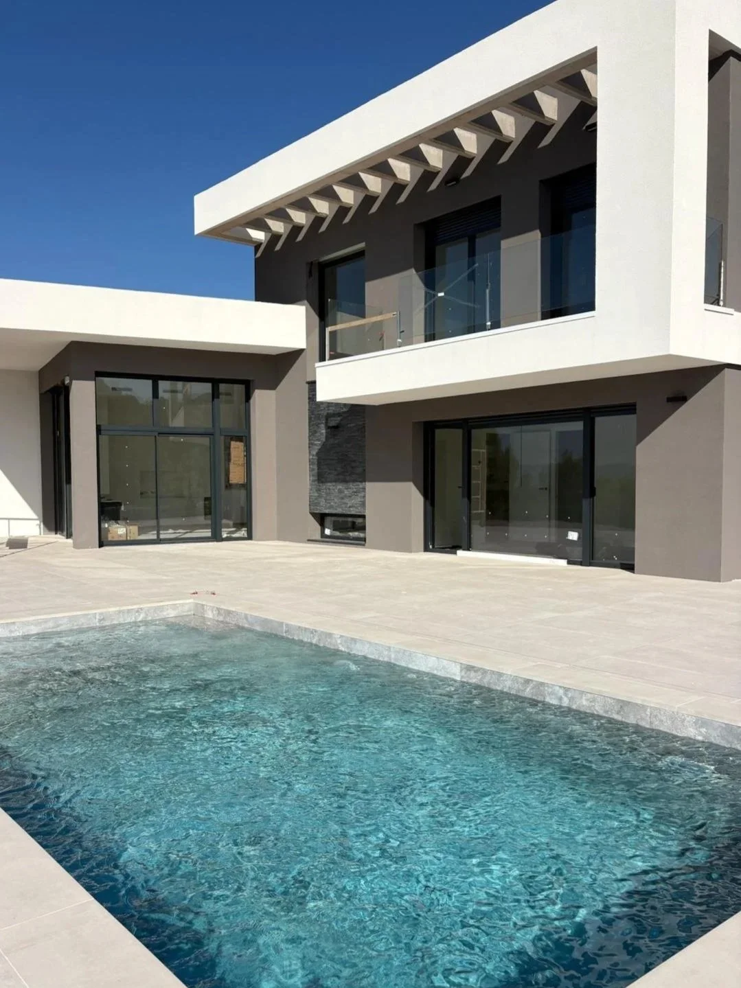 Fachada de vivienda unifamiliar en UIlastrell con piscina y barandillas de vidrio.